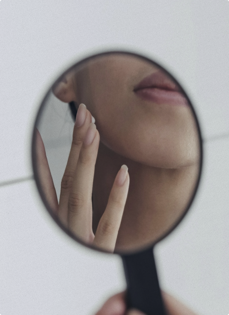 Close-up of woman examining her skin with a magnifying glass