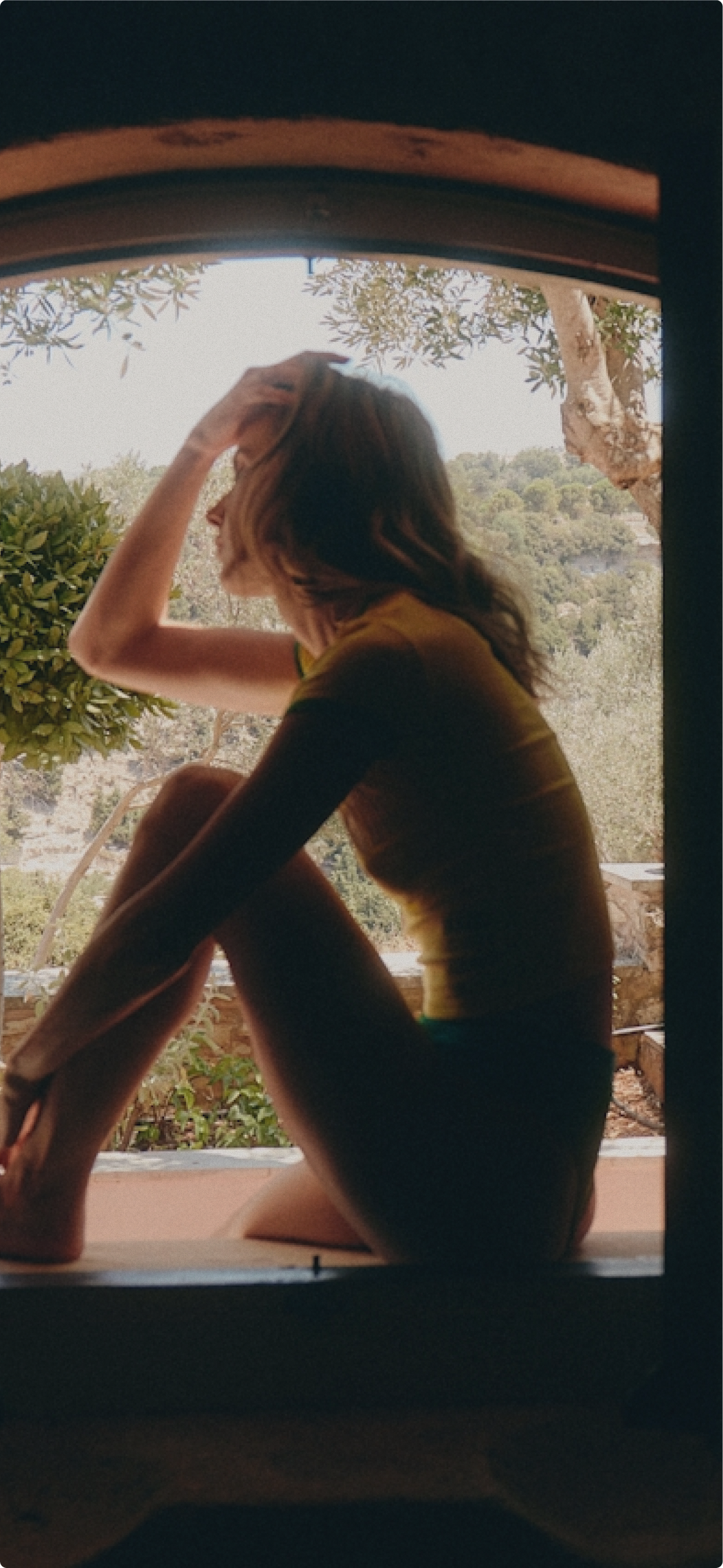 Woman seated by a window looking outside