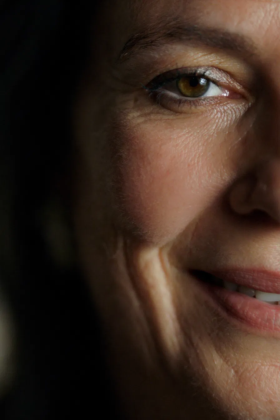 Close-up of a woman's eye and under-eye area with warm, dramatic lighting