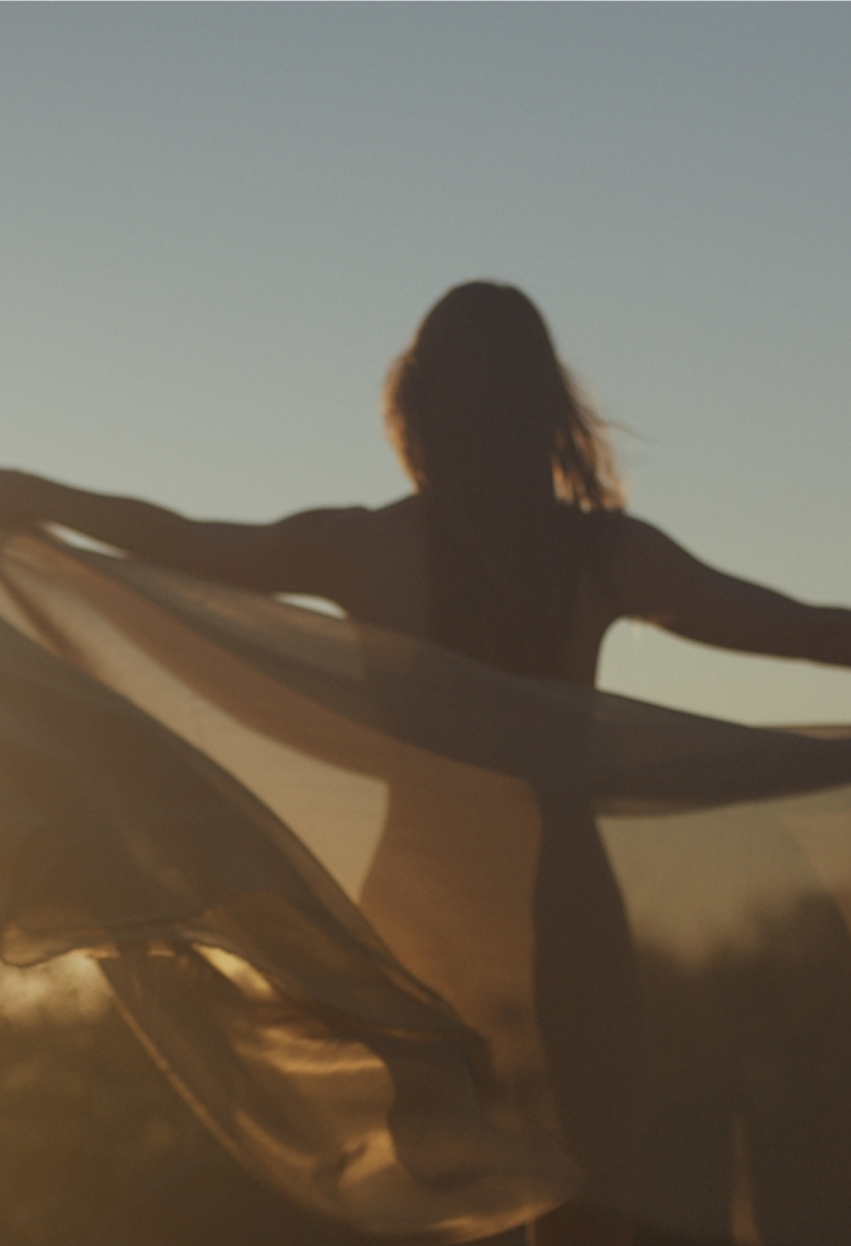 Woman standing outdoors with fabric blowing in the wind