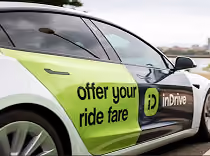 White and green car with inDrive branding and text reading offer your ride fare on the door.