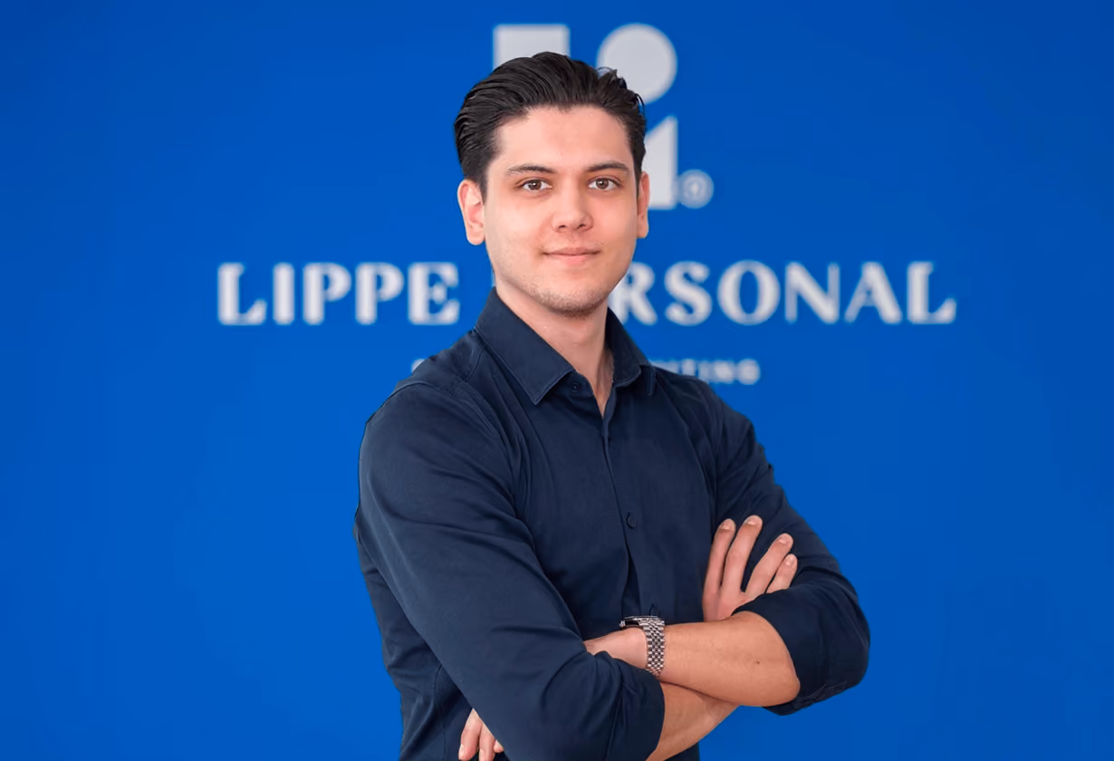Mann mit schwarzen Haaren, verschränkten Armen, trägt ein dunkles Hemd vor blauem Hintergrund mit Lippe Personal-Logo.