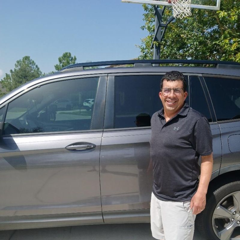 Smiling woman in green shirt giving thumbs up next to a silver SUV Before and after mobile bumper scrape repair by Paint N Go