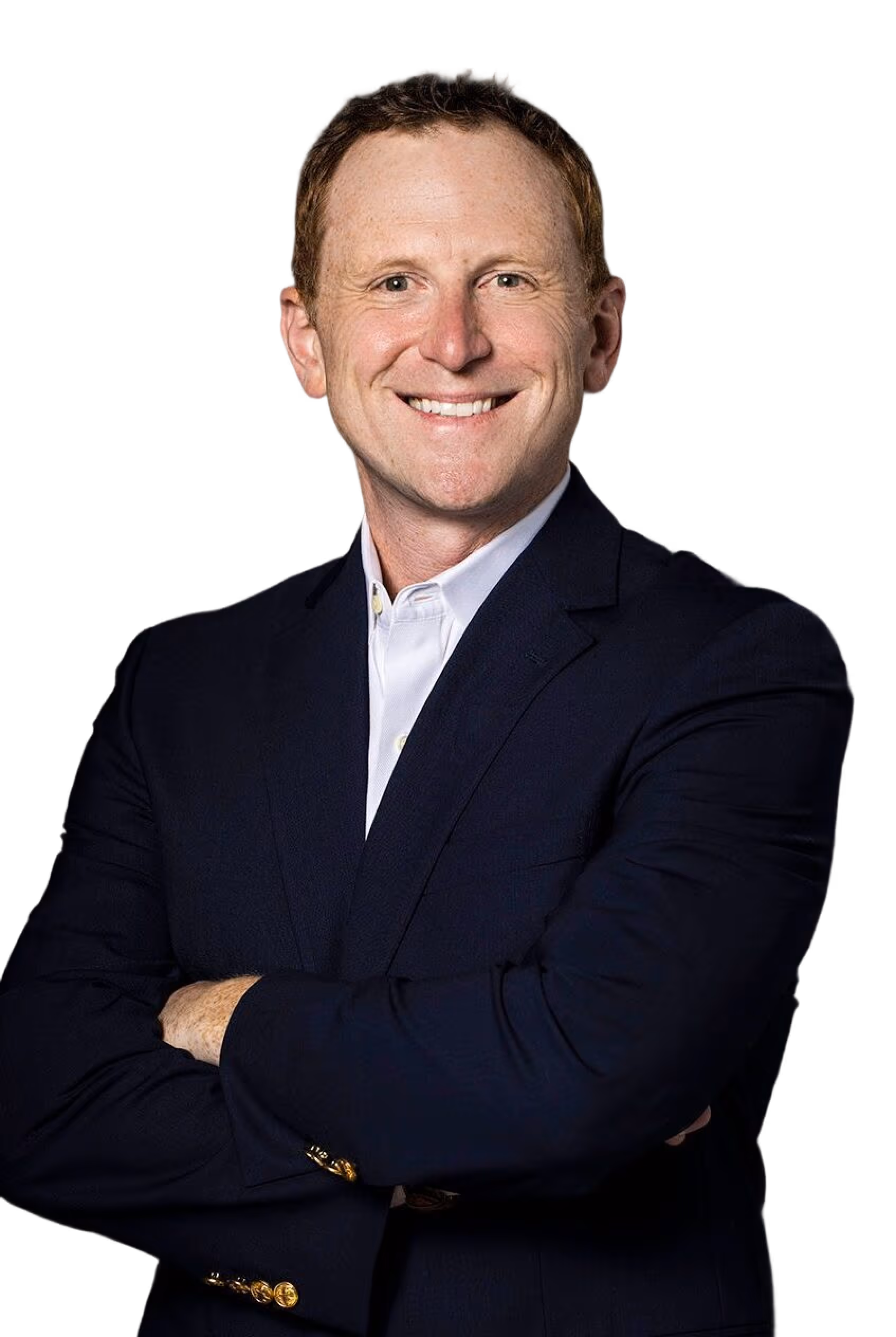Smiling man with crossed arms wearing a dark suit jacket and white shirt against a black background.