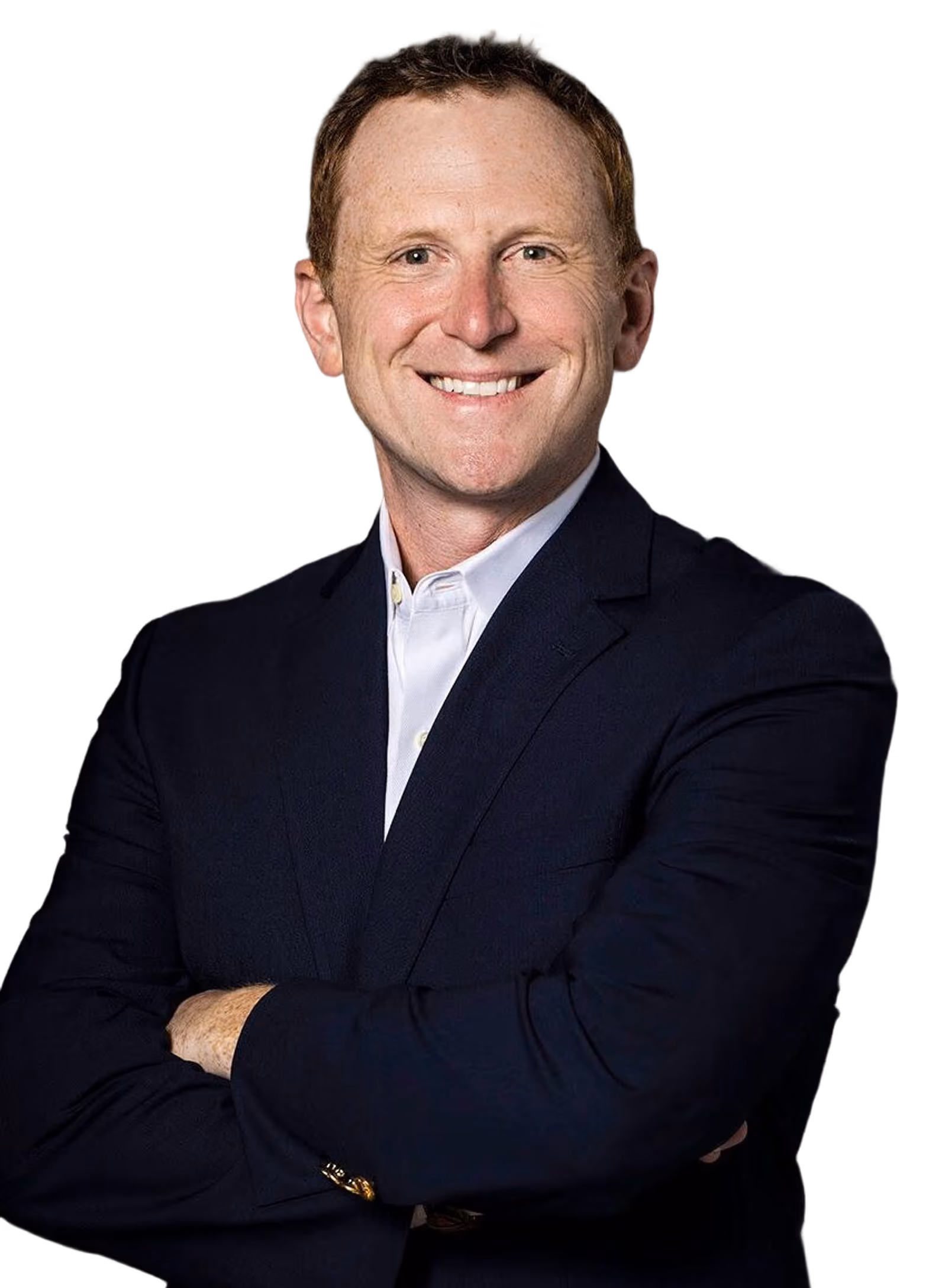 Smiling man with crossed arms wearing a dark suit jacket and white shirt against a black background.