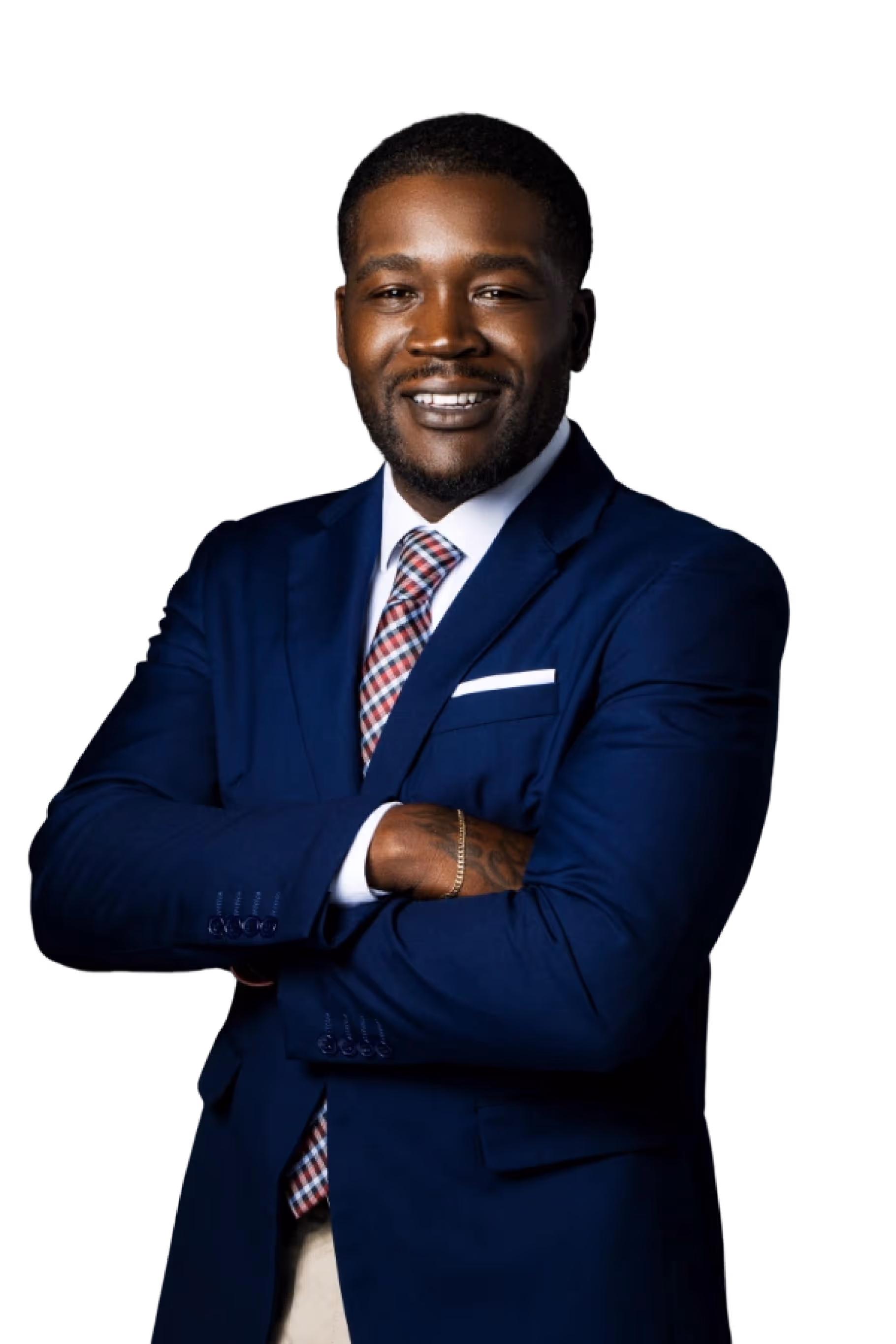Smiling man in a blue suit with a white shirt and checkered tie standing with arms crossed against a black background.