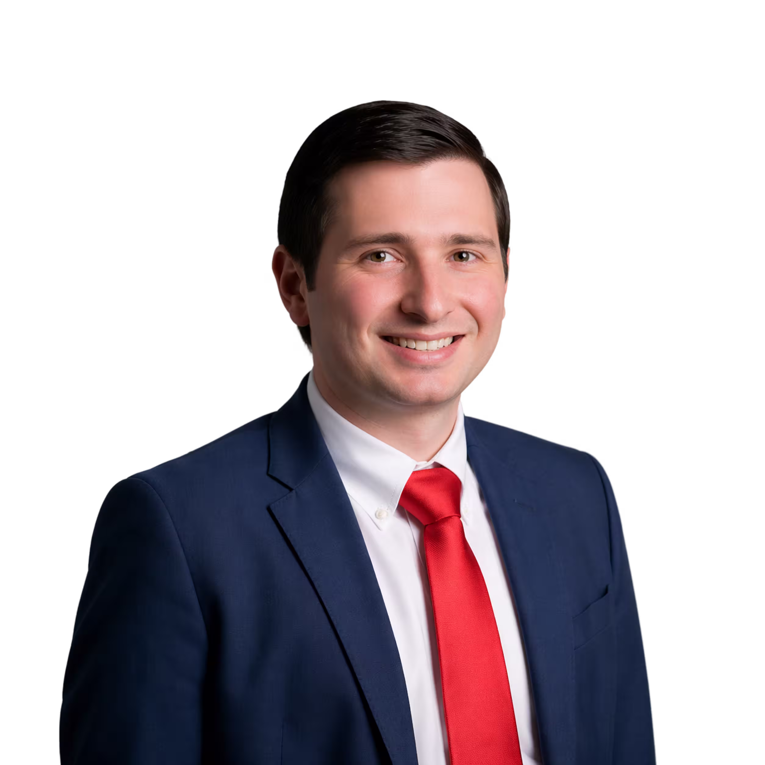 Smiling man with dark hair wearing a navy blue suit, white shirt, and red tie against a black background.
