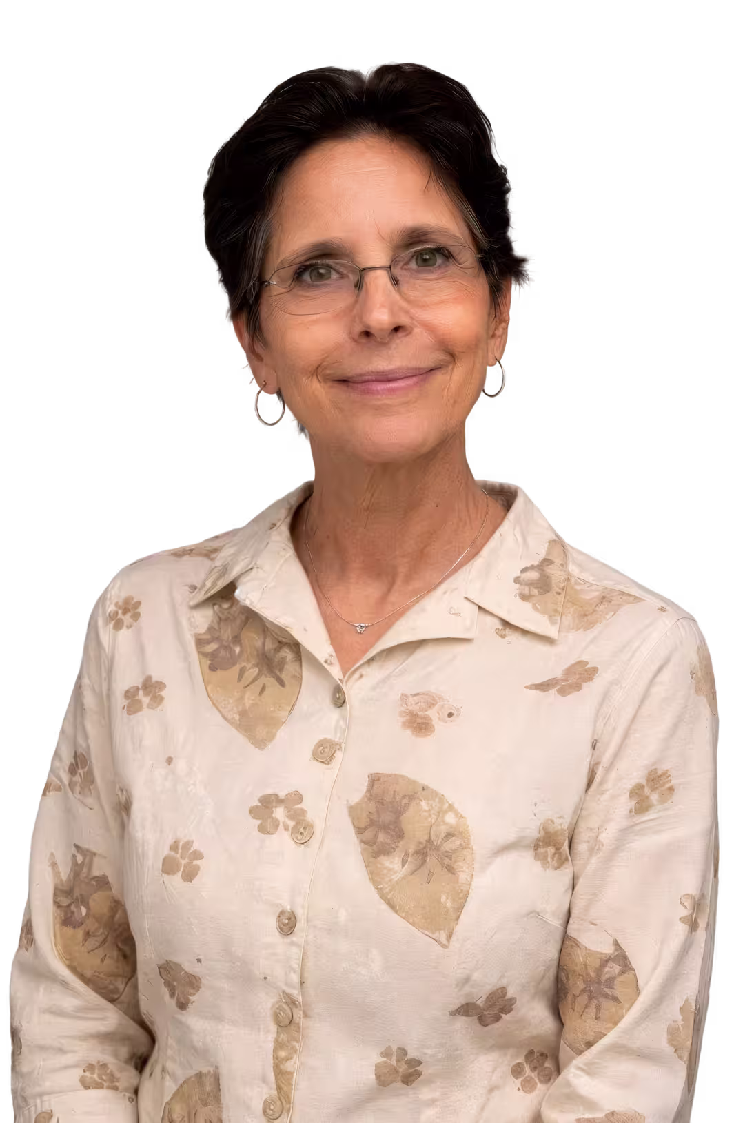Smiling middle-aged woman with short dark hair, glasses, silver hoop earrings, and a beige floral patterned button-up shirt.