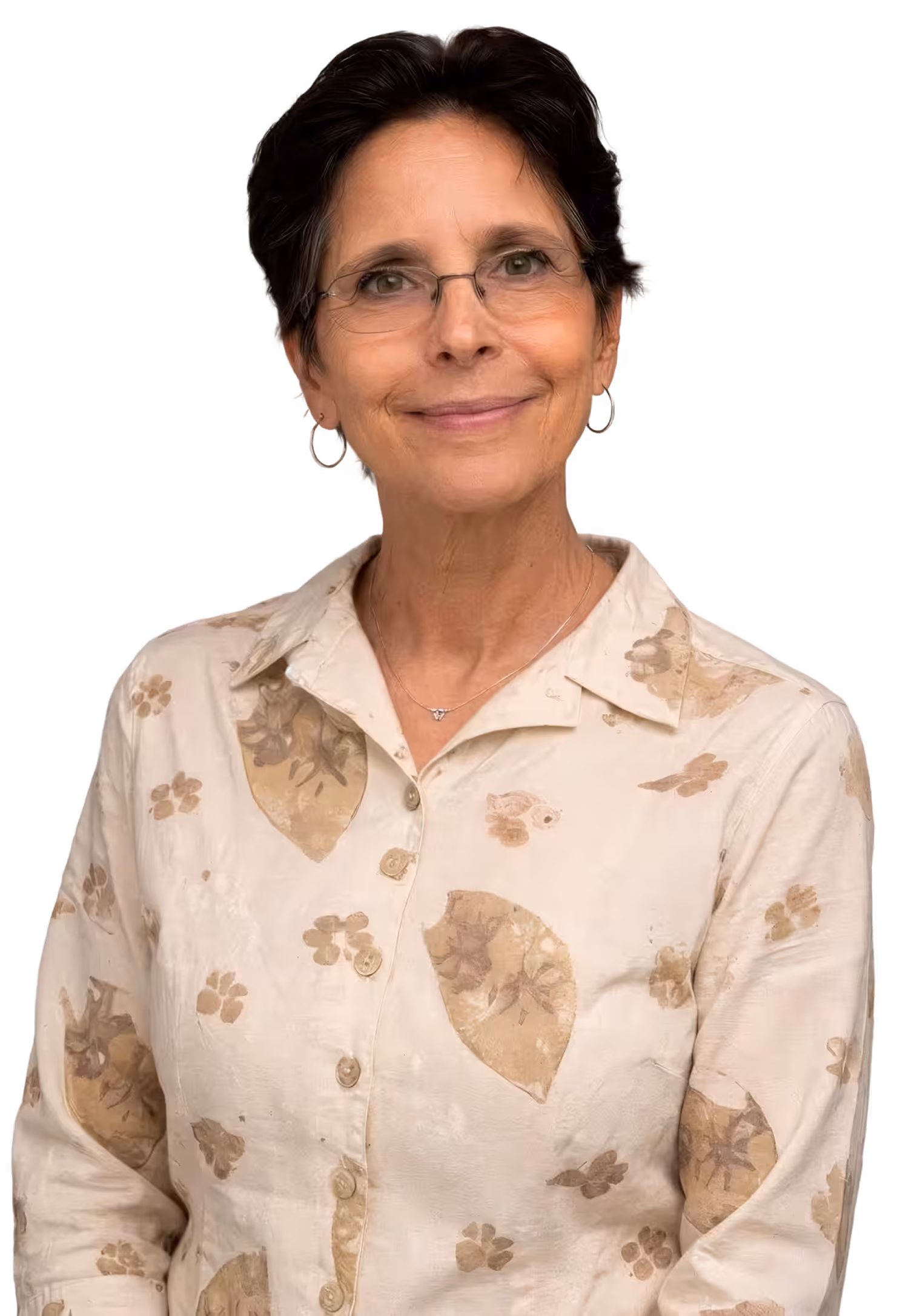 Smiling middle-aged woman with short dark hair, glasses, silver hoop earrings, and a beige floral patterned button-up shirt.