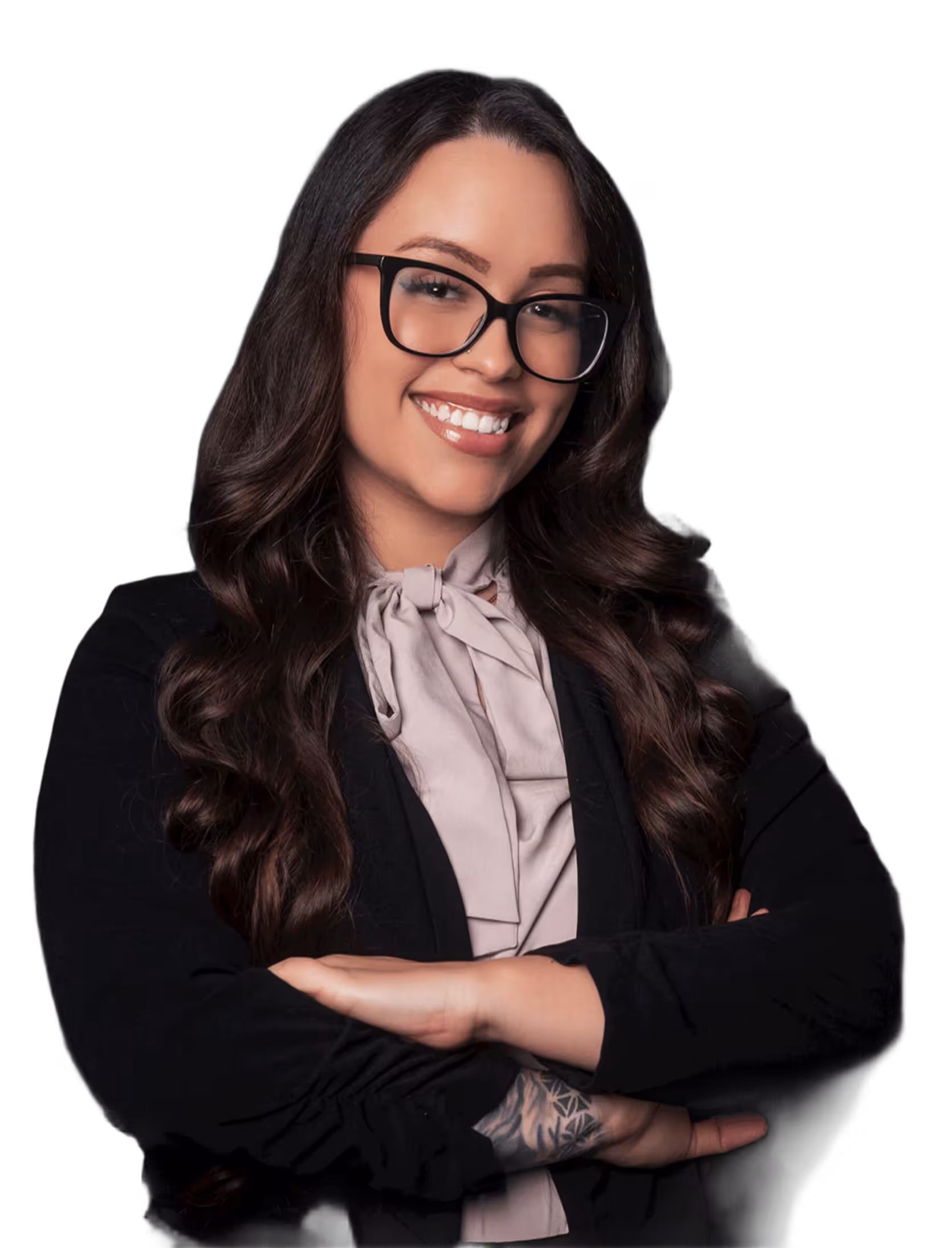 Smiling woman with long wavy brown hair and glasses, wearing a black jacket with arms crossed.