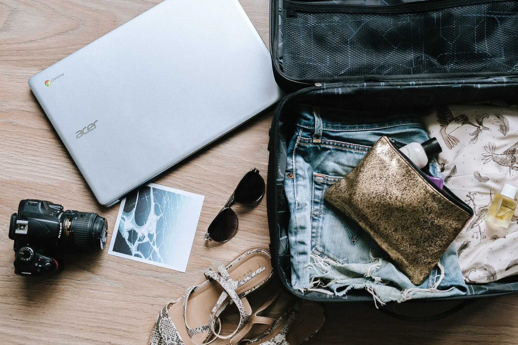 Opened suitcase, a laptop, camera and sunglasses