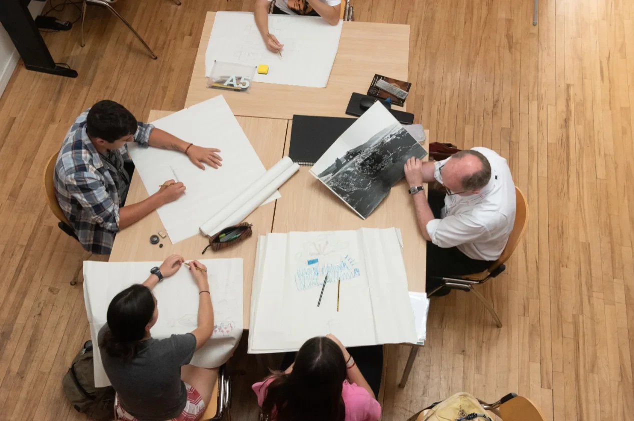 People drawing on papers on a desk