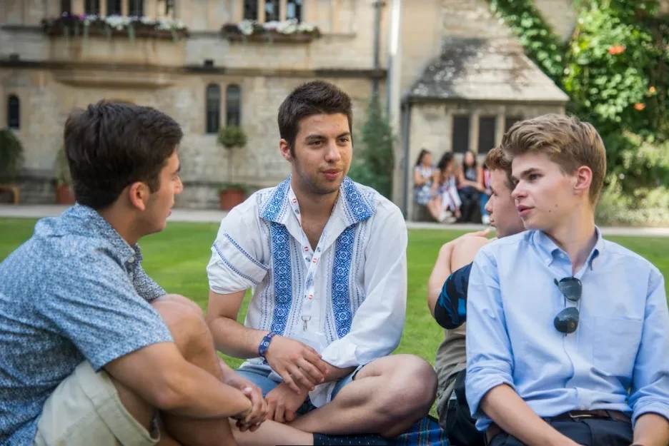 Three students sitting on grass and talking