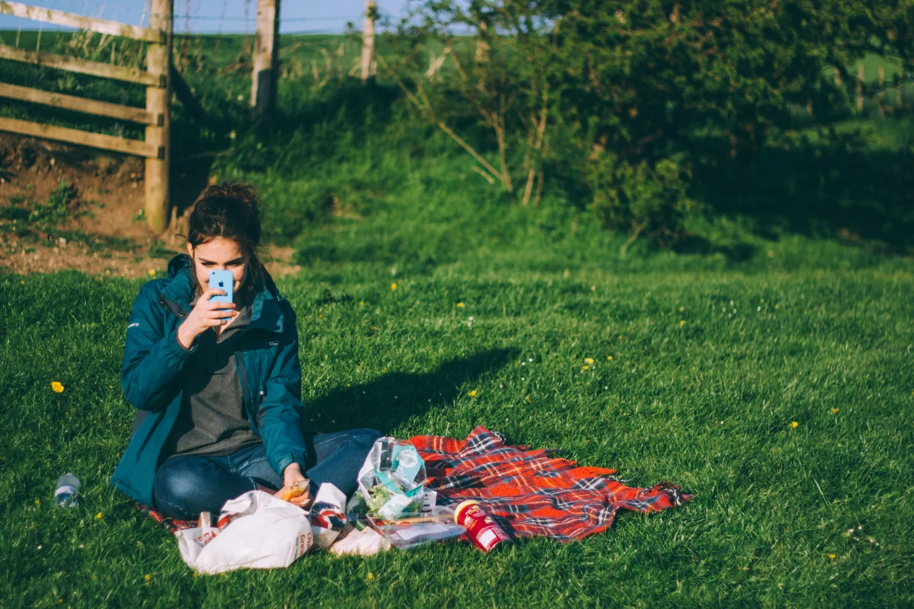 A girl sitting on grass and taking a picture