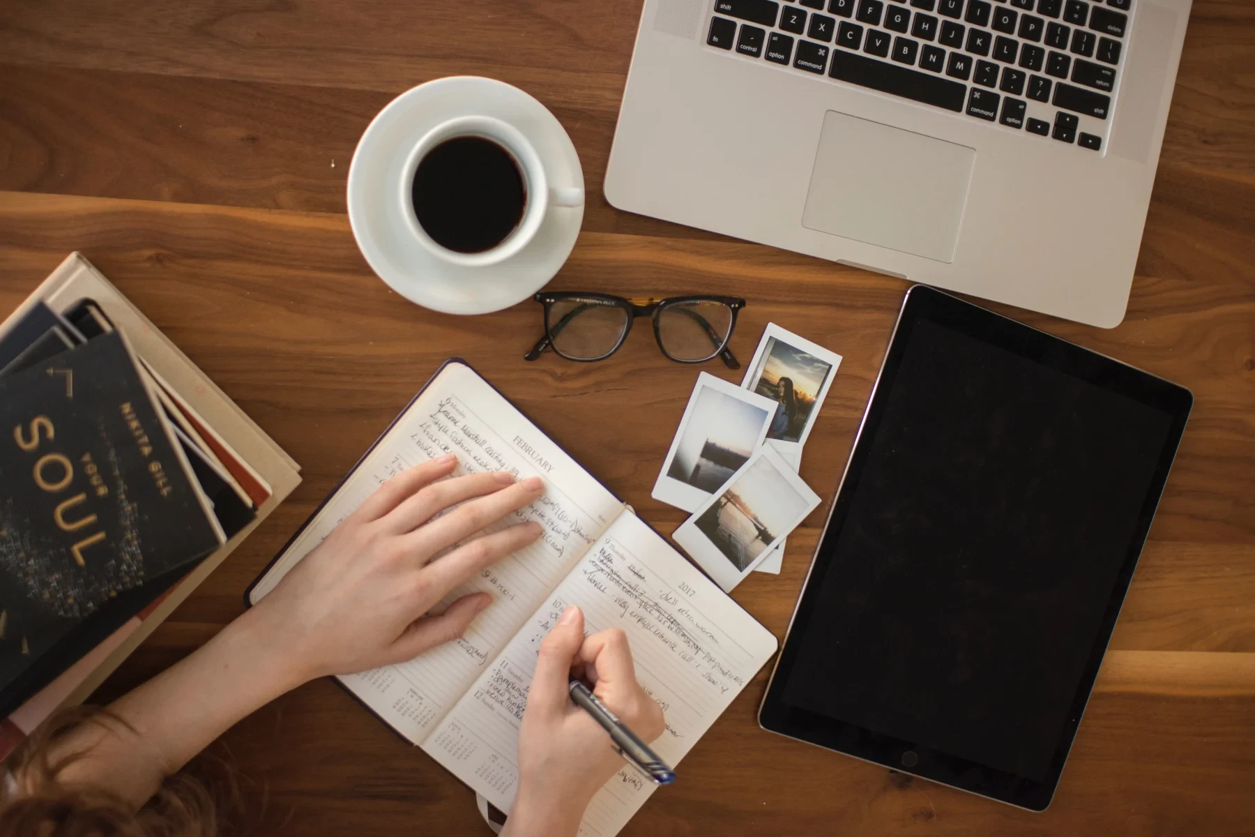 Opened notebook, coffe, glasses, tablet and polaroids on a table