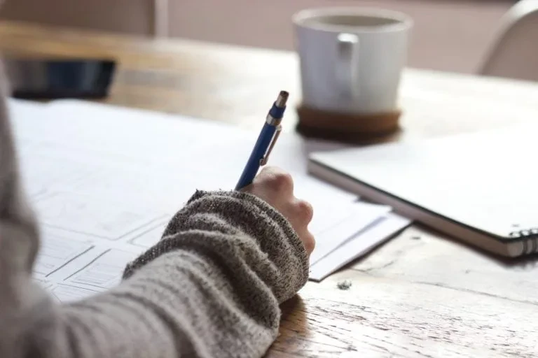 A person writing with a pen