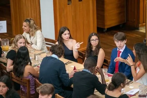 Group of students at Oxford summer school chatting with a teacher outdoors on a sunny day.