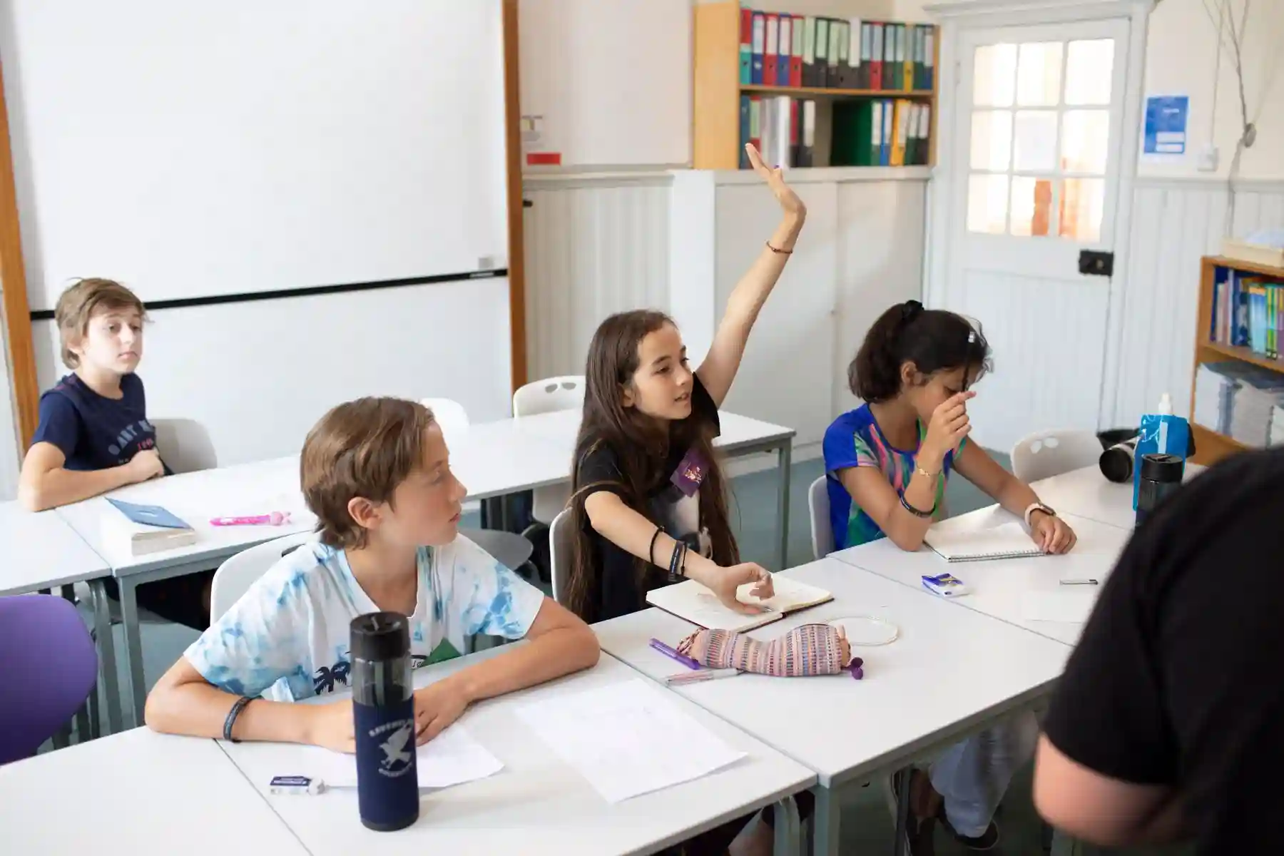 Kid in a classroom raising hand