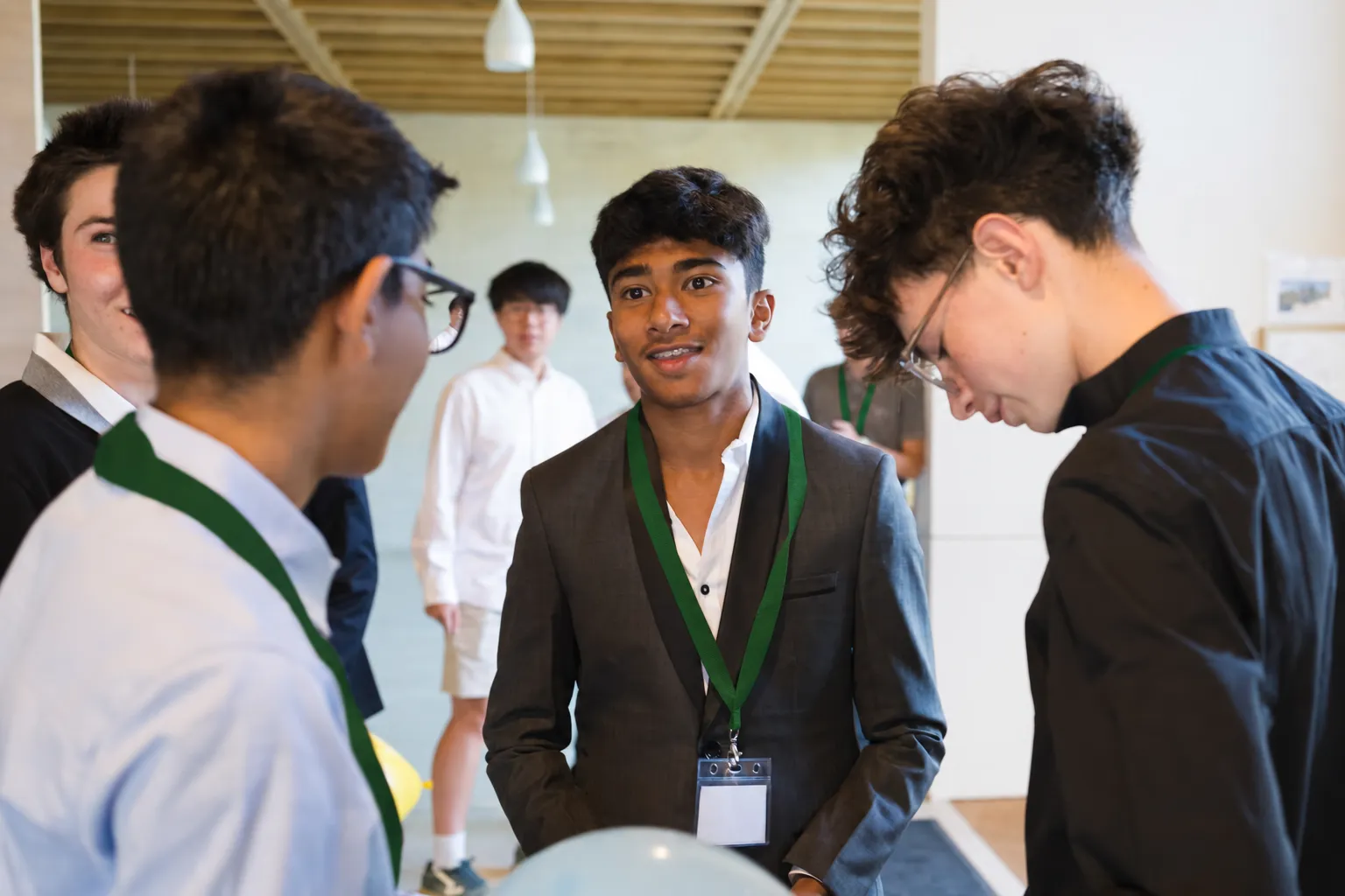 Group of students in green lanyards talking together indoors between sessions
