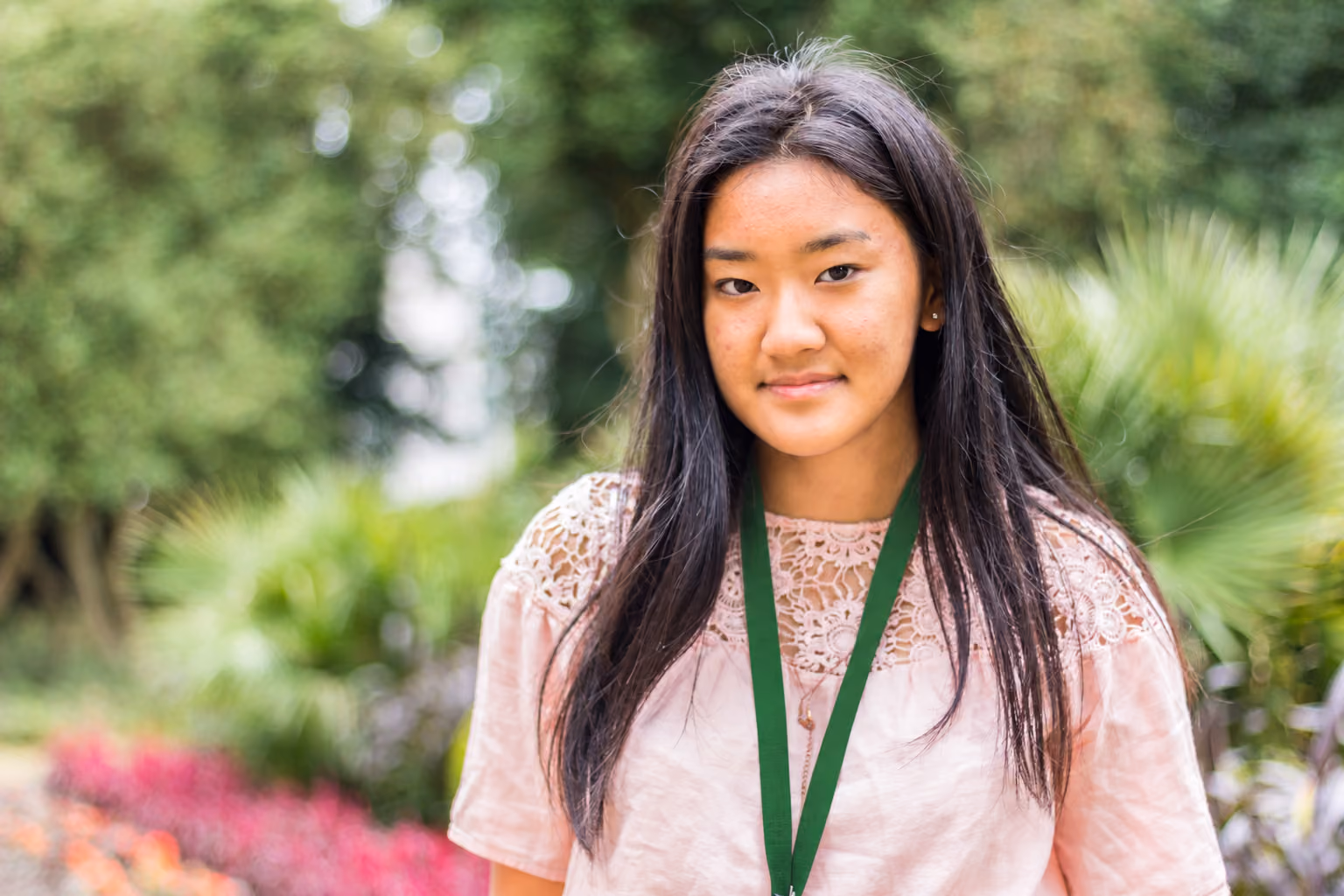 Portrait of a student wearing a green lanyard in a garden