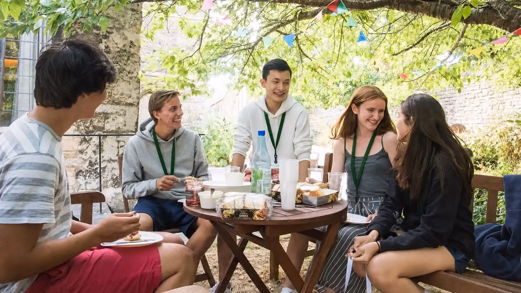 Students sharing food around an outdoor table under bunting in Oxford