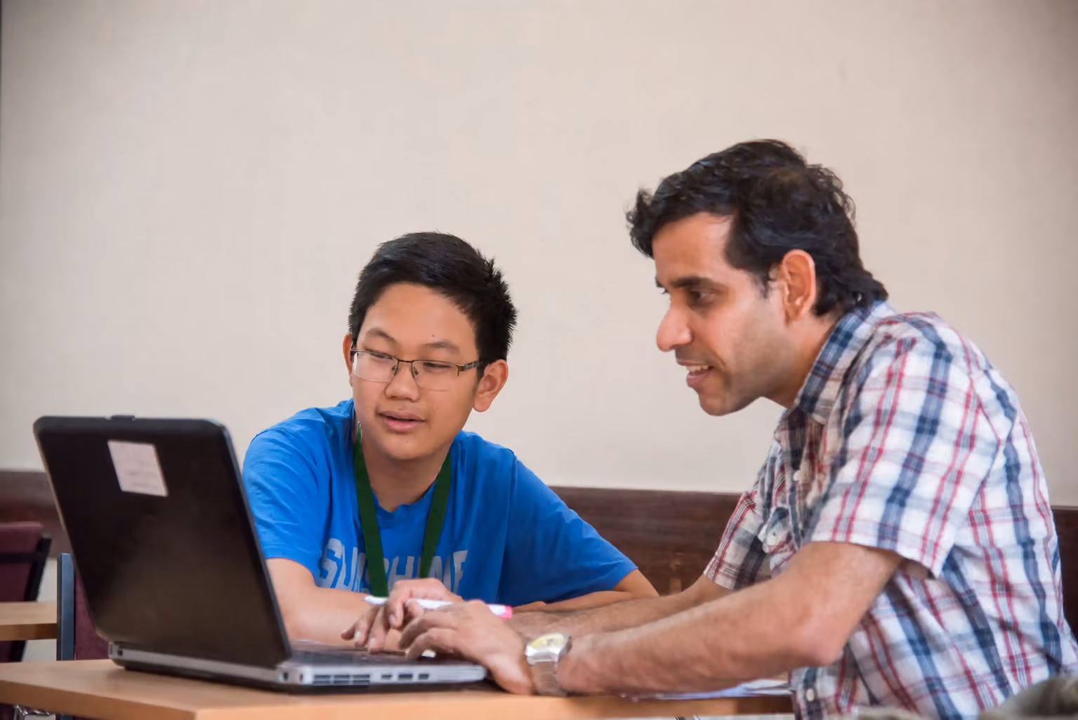 Tutor helping a student with their work at a laptop during a class in Cambridge