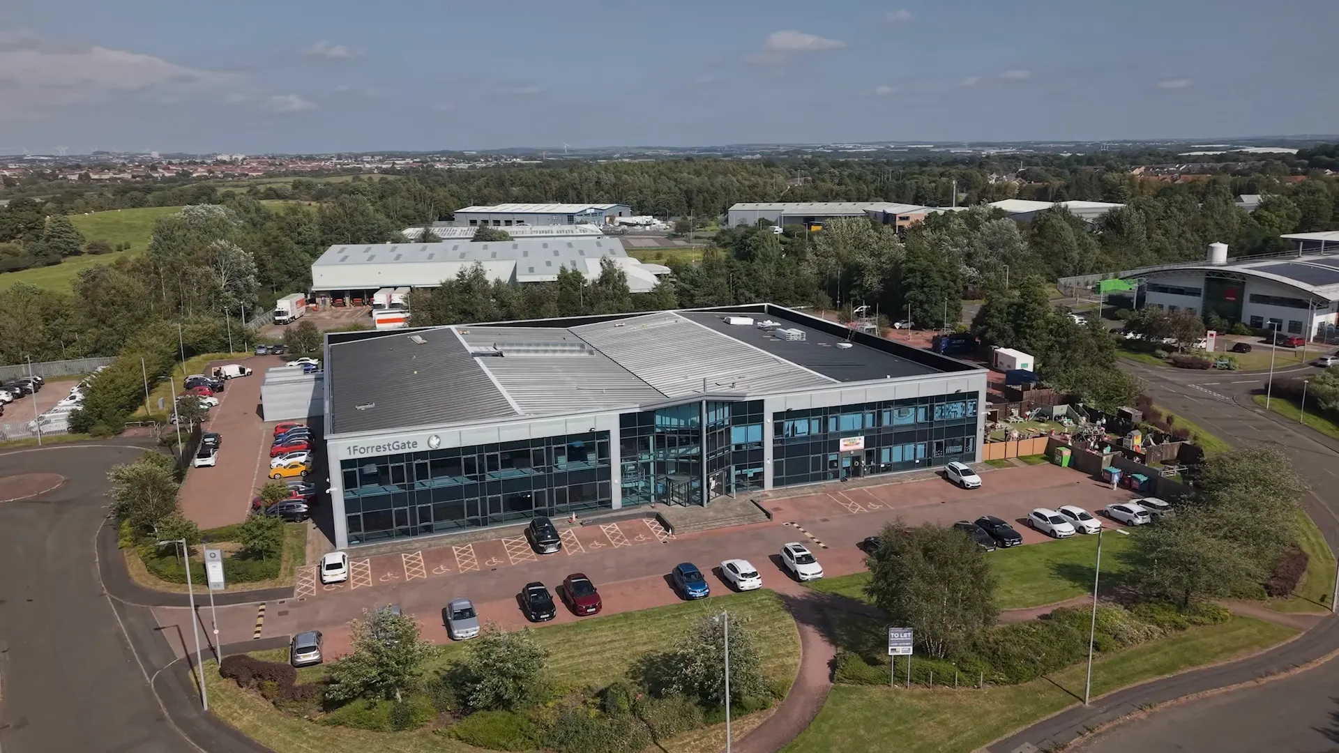 Wide aerial view of the DFYNE project in Glasgow, showing the metal roof, glazed frontage and surrounding grounds.