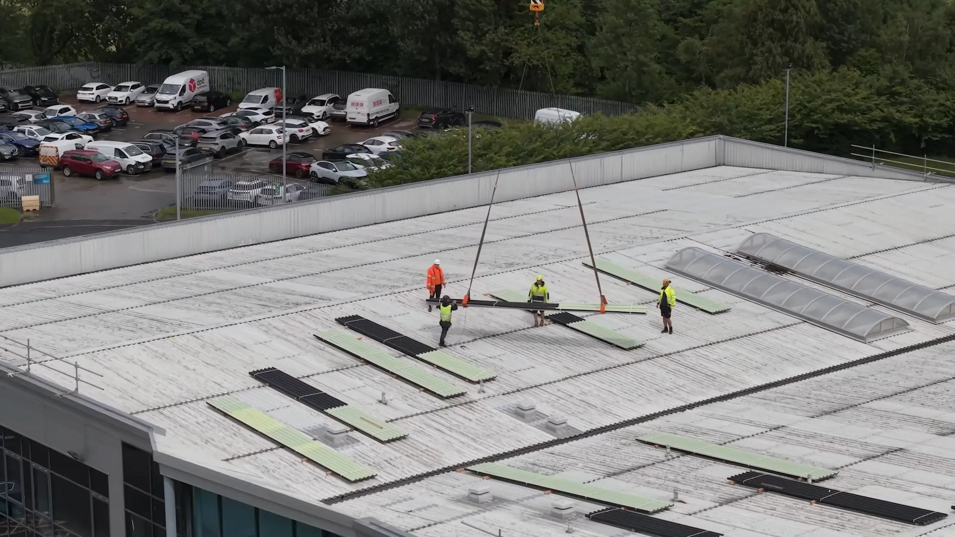 Roofing team guiding metal panels during a crane lift at the DFYNE project in Glasgow.