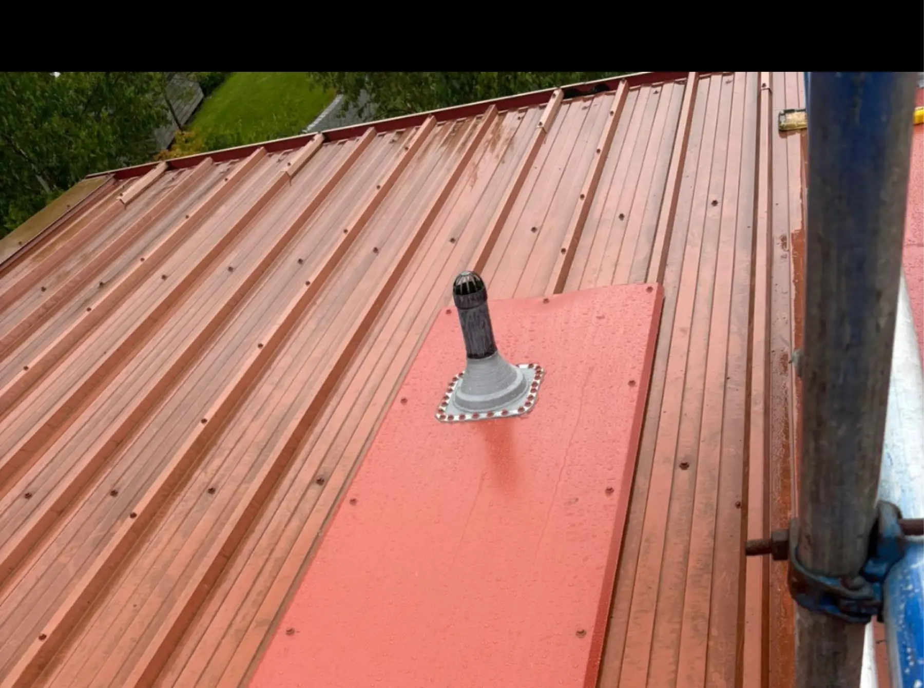 Vent pipe sealed with a flashing boot through a new flat sheet on a red profiled metal roof, Team Services, Glasgow