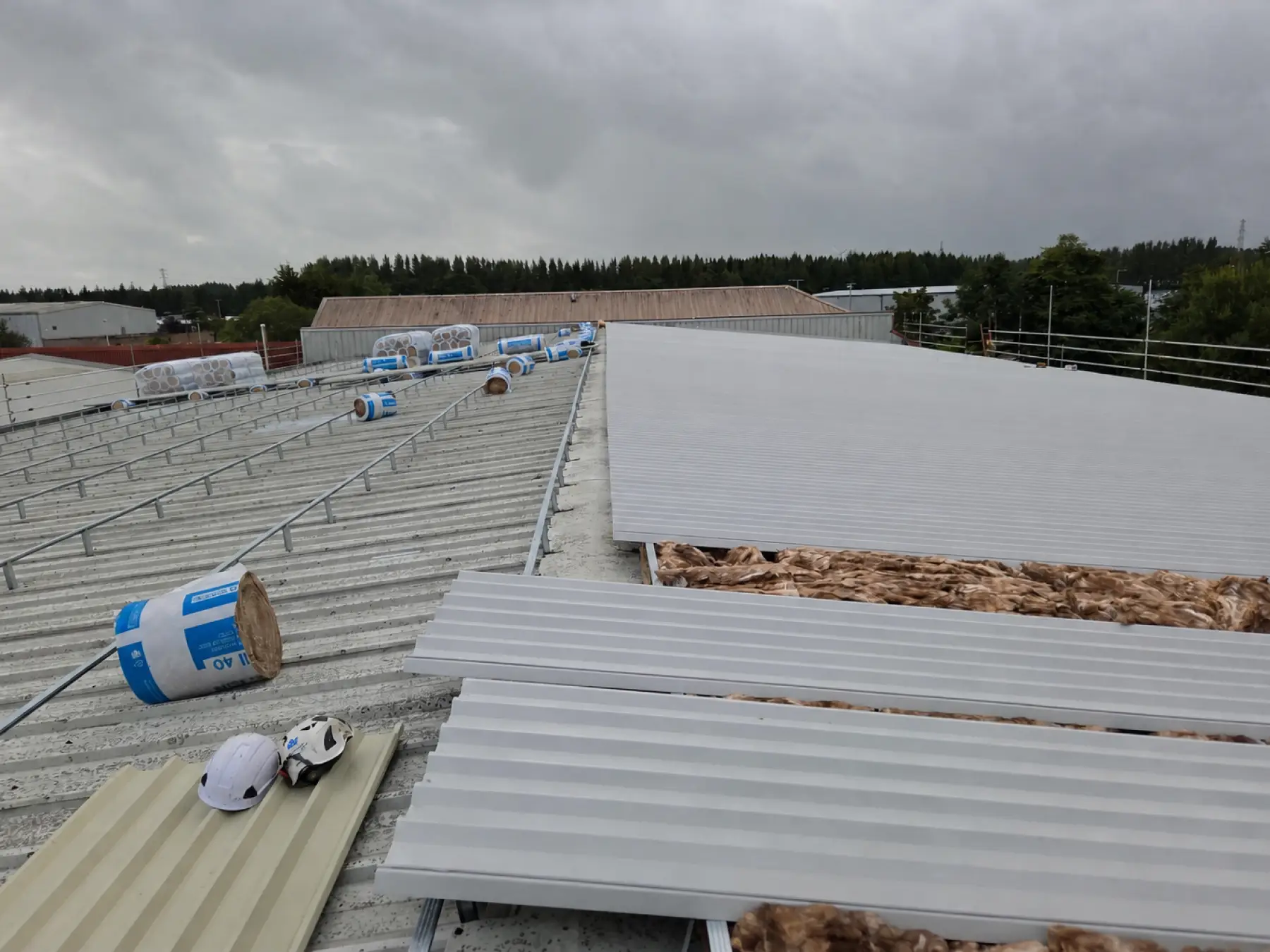 New metal sheets over mineral wool beside the old roof, rails and insulation rolls at Phoenix Medical, East Kilbride