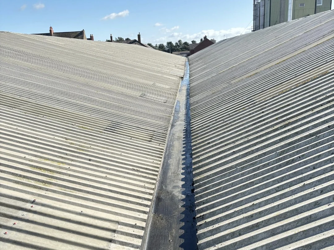 Valley gutter between two corrugated industrial roofs on a Cumbria gutter-cleaning project.