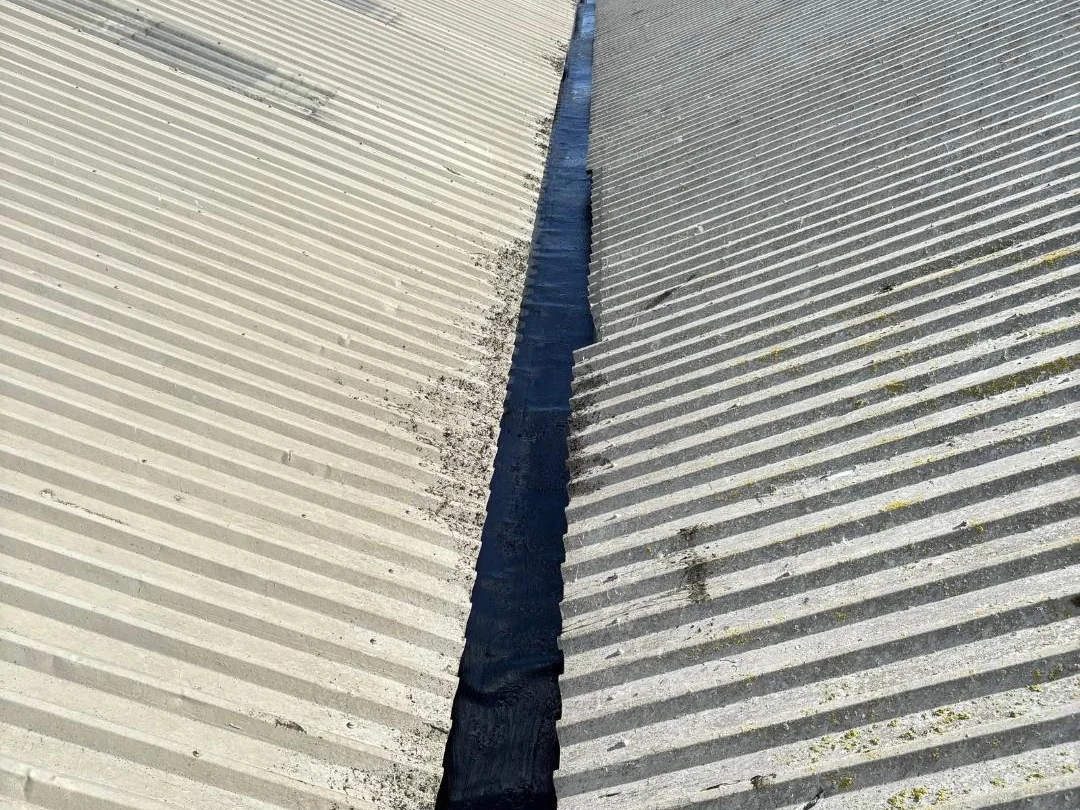 Close view along an industrial valley gutter between corrugated roof sheets in Cumbria.