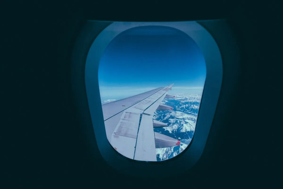 Pogled kroz prozor aviona na krilo i planine