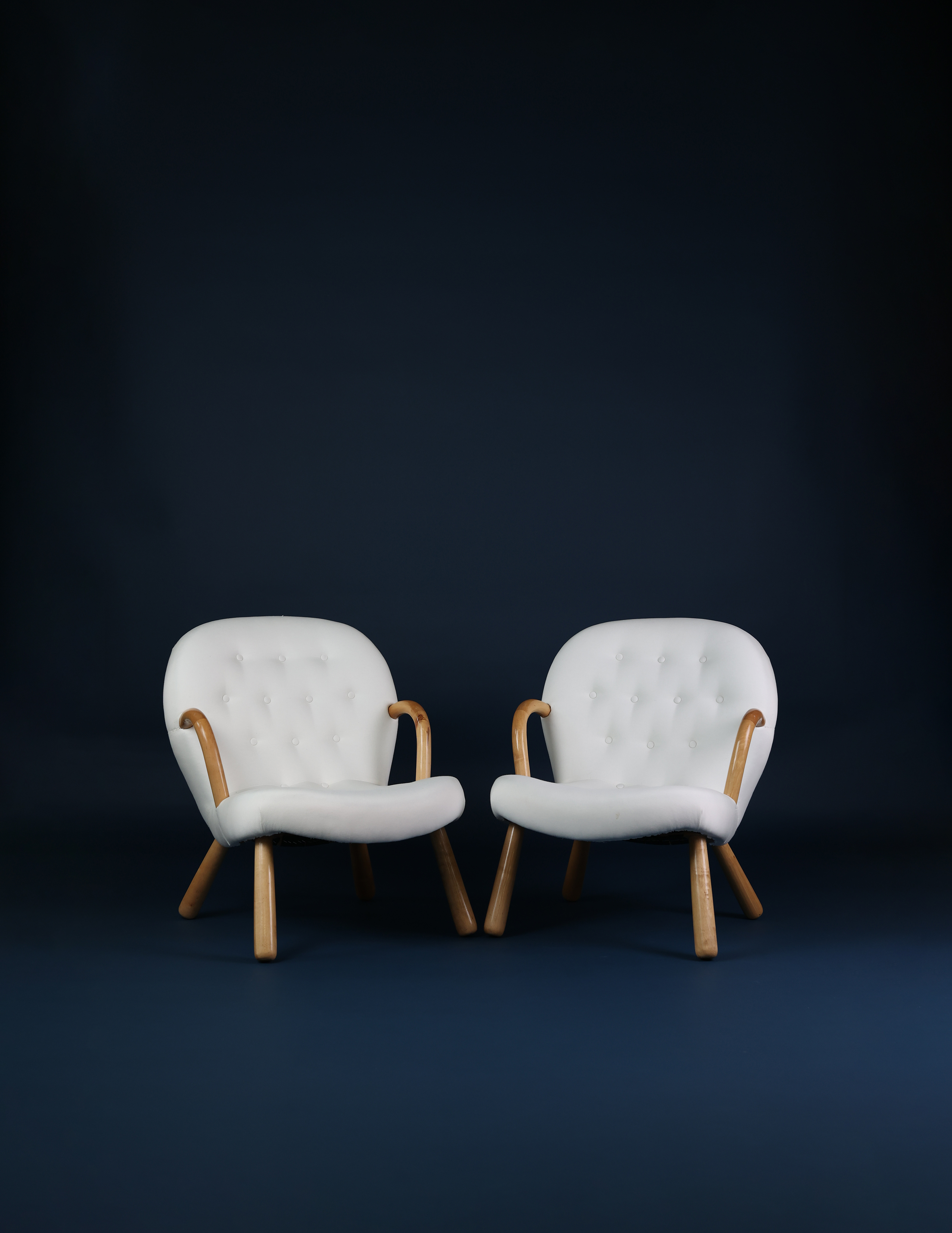 Pair of Arnold Madsen Clam lounge chairs upholstered in white shearling with Scandinavian wooden legs.