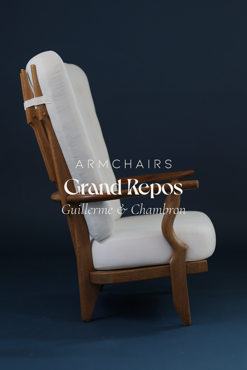 Grand Repos armchair by Guillerme et Chambron - full front view with white fabric upholstery and solid oak frame on a dark blue background