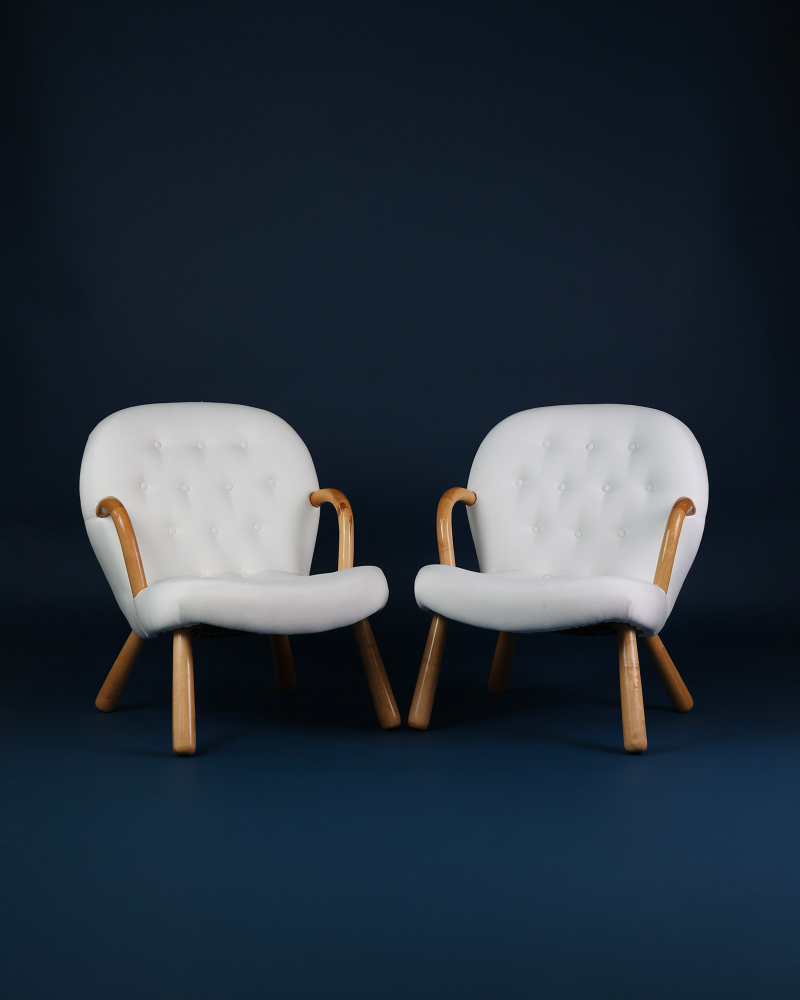 Pair of Arnold Madsen Clam lounge chairs upholstered in white shearling with Scandinavian wooden legs.