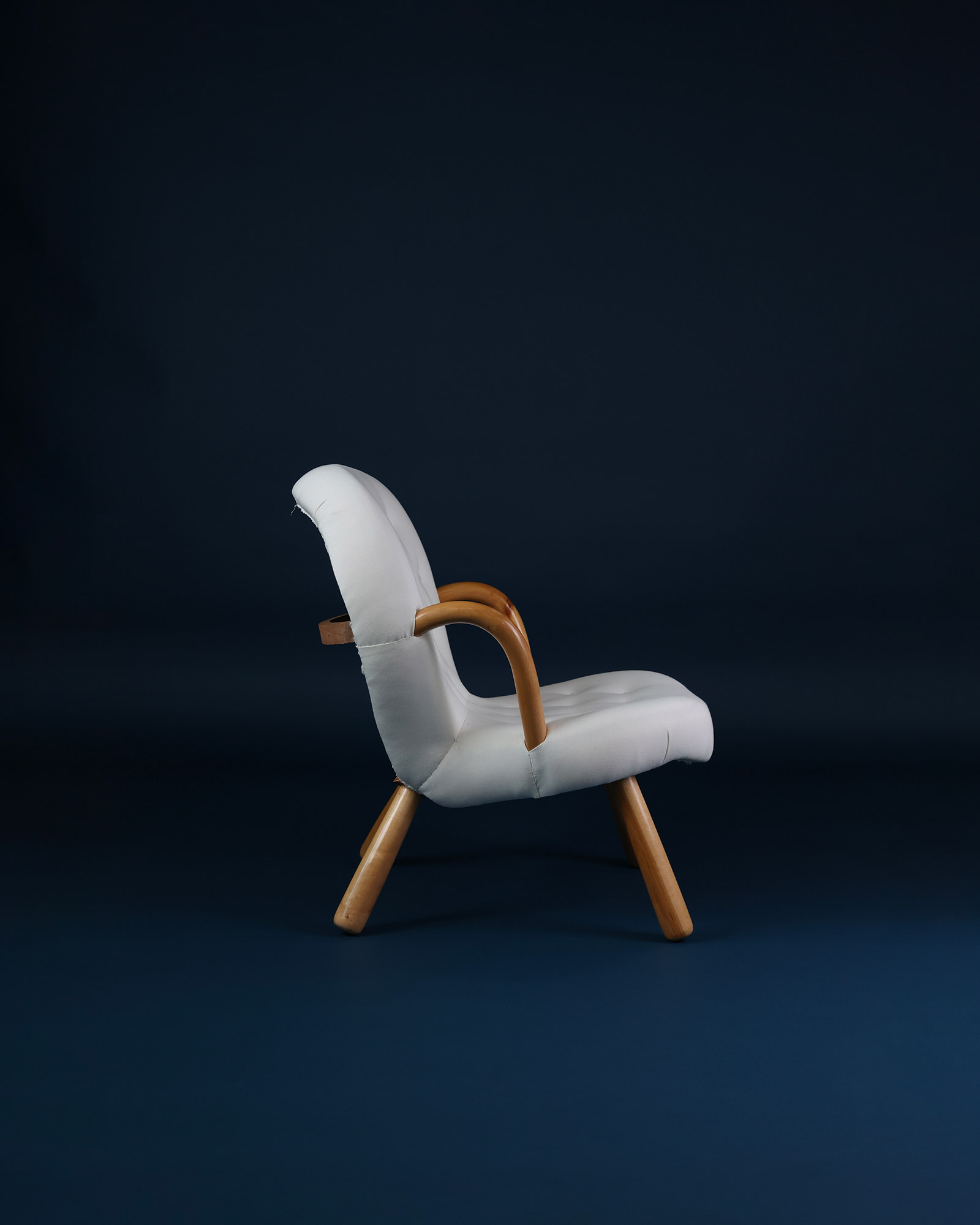 Side profile view of the iconic Danish design Clam chair by Arnold Madsen showing curved wooden arms.