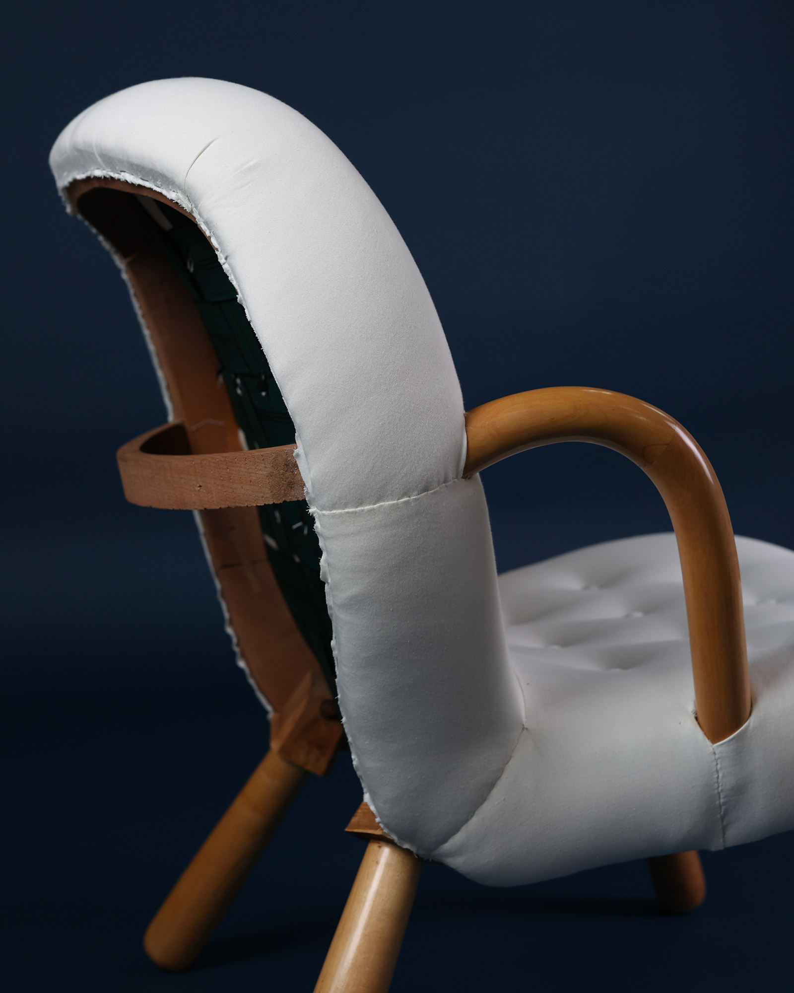 Close-up detail shot of the white shearling texture and crafted wooden armrest on the Arnold Madsen Clam chair.