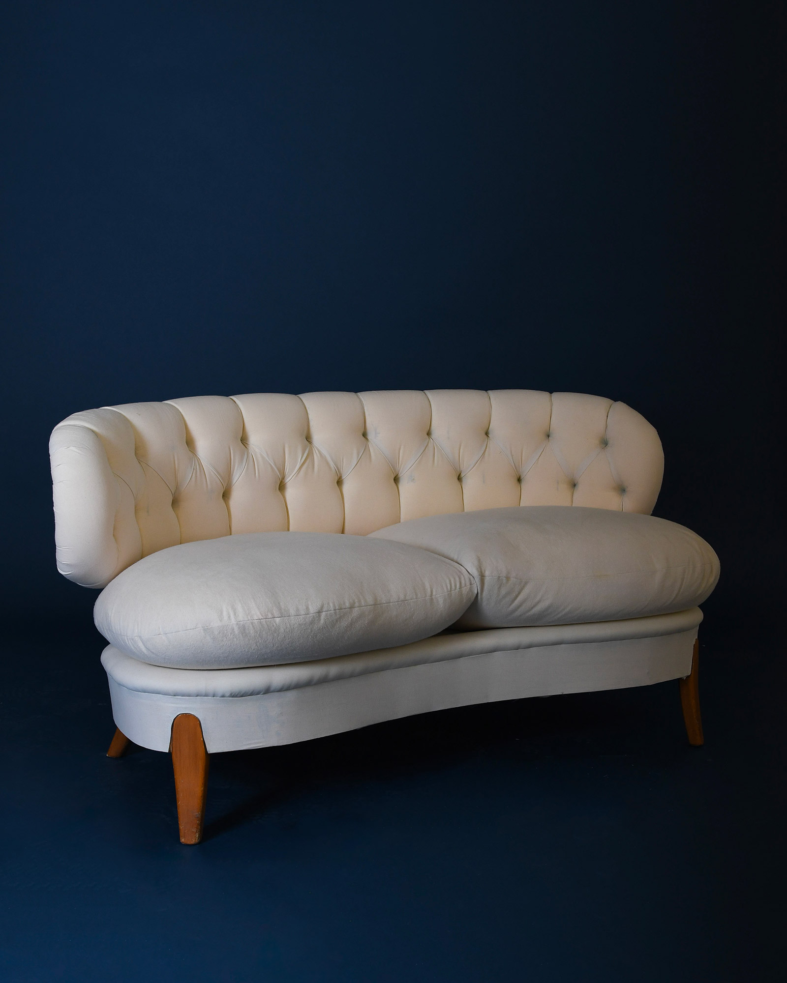 A three-quarter view of the right side of the Otto Schulz Boet sofa, showcasing the curvature of the armrest, the textured fabric, and the dark wood base.