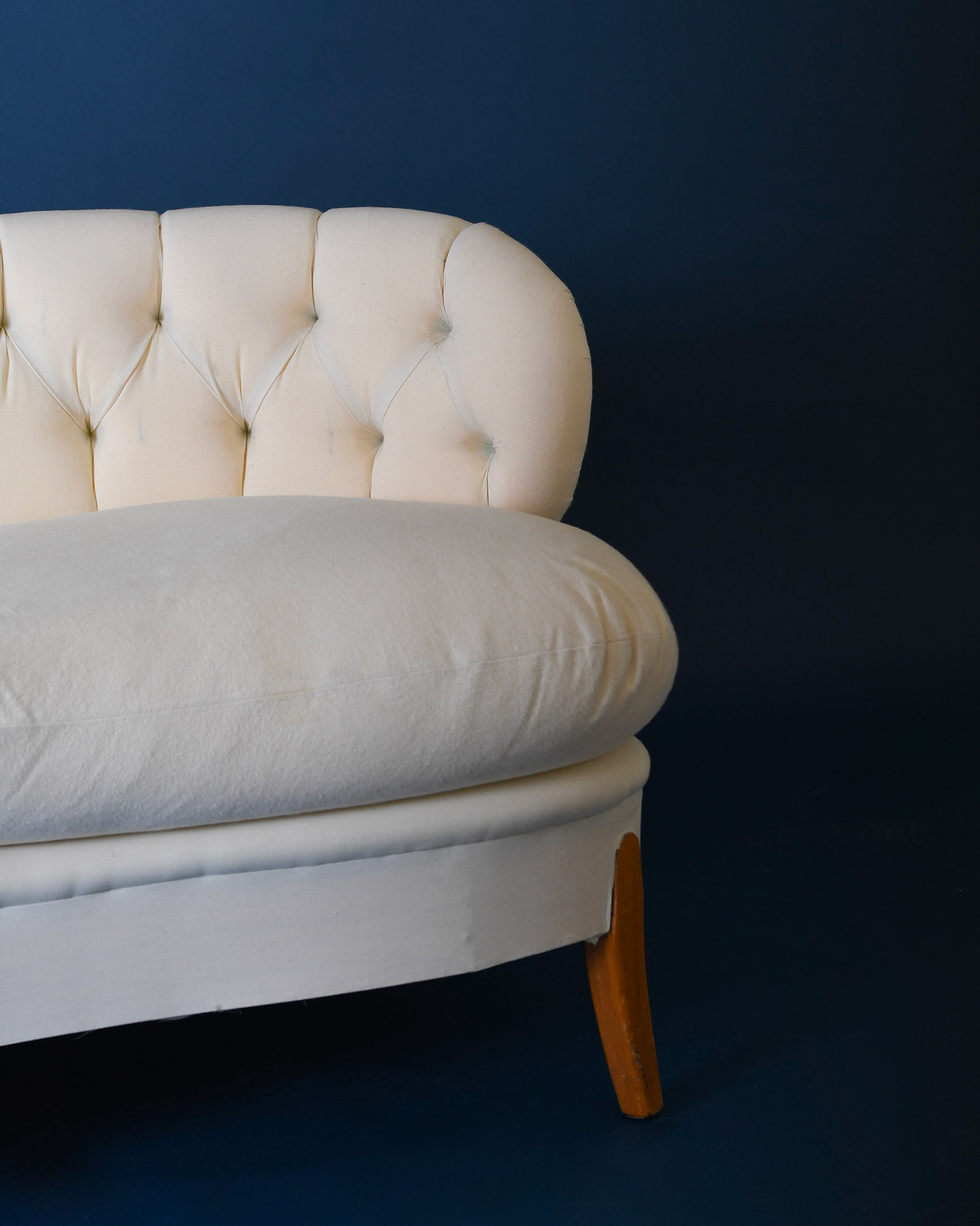 A detailed view focusing on the left-side end of the cream Boet sofa by Otto Schulz, showing the plush seating cushions and the profile of the button-tufted back.