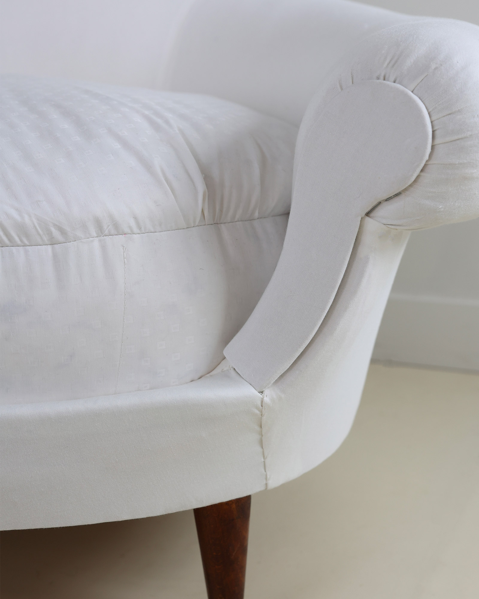 Munari curved sofa by Federico Munari - close-up detail of the side profile, upholstery stitching, and wooden leg