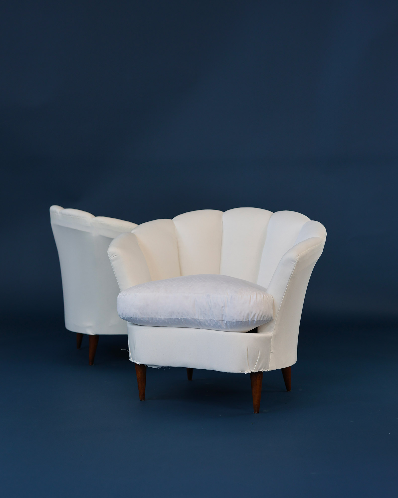 Pair of 1950s Italian armchairs by Gio Ponti - angled composition on a dark blue studio background