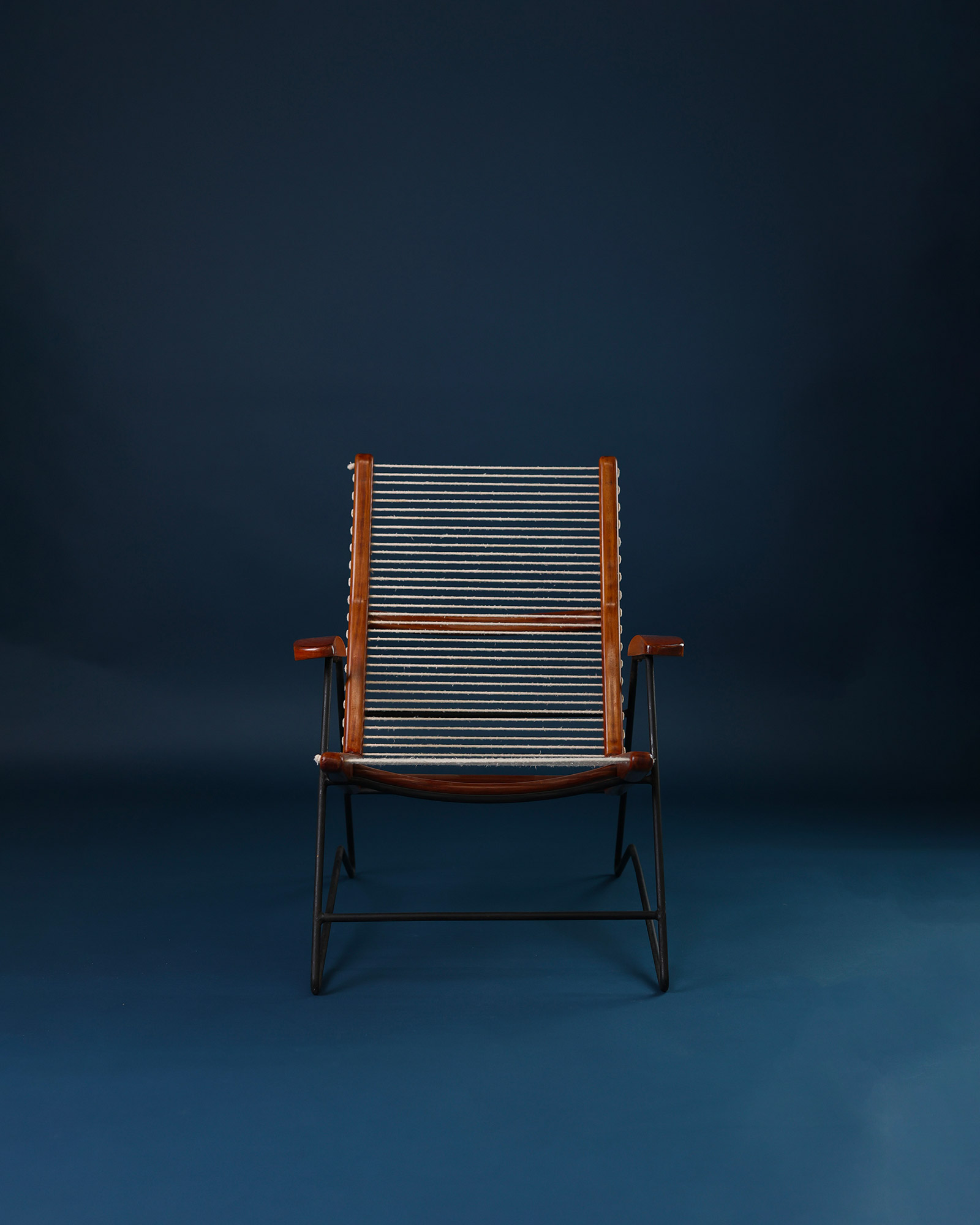 String armchair by Carlo Hauner - full front view with white cushions on a dark blue background