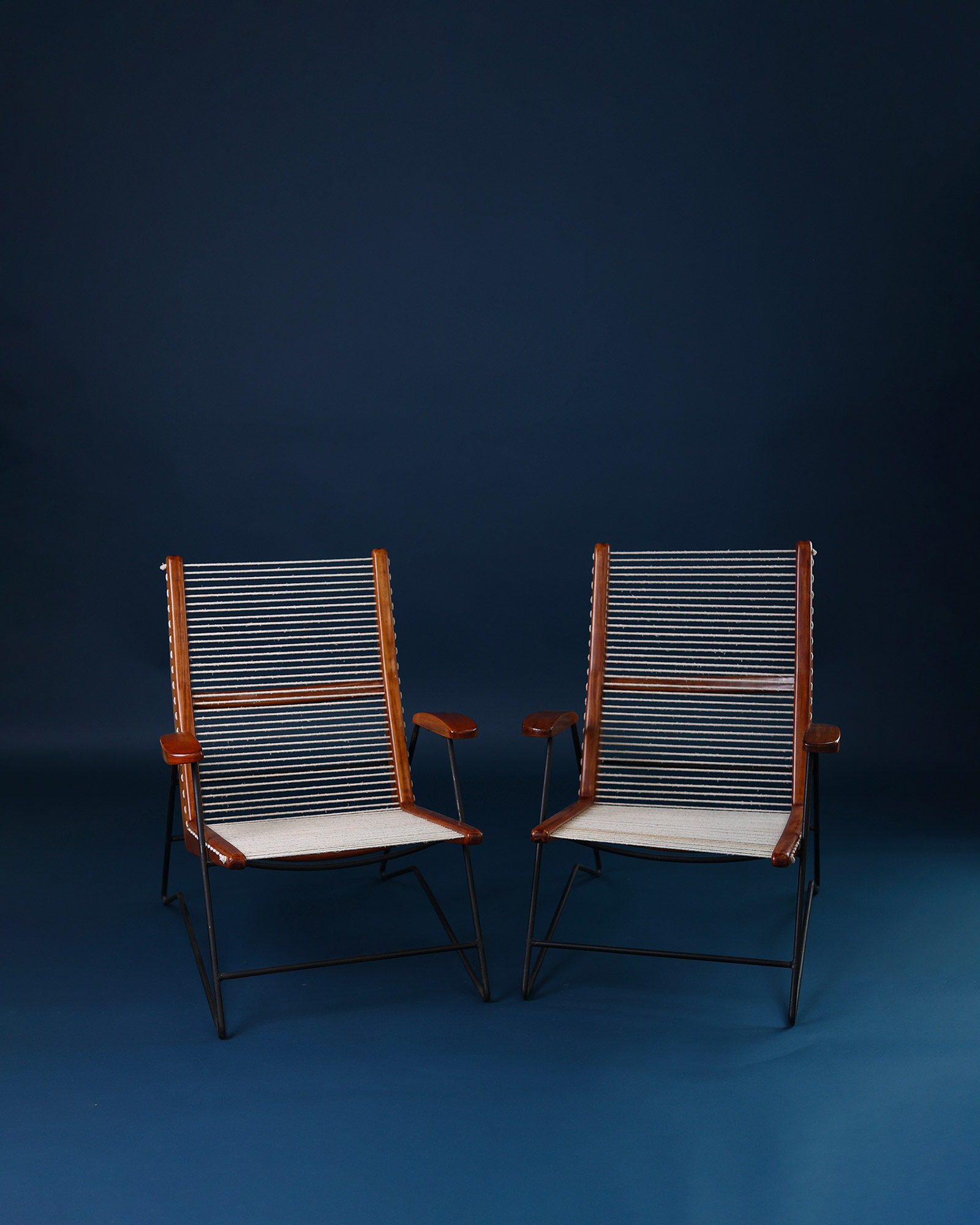 Pair of String armchairs by Carlo Hauner - side-by-side composition on a dark blue background