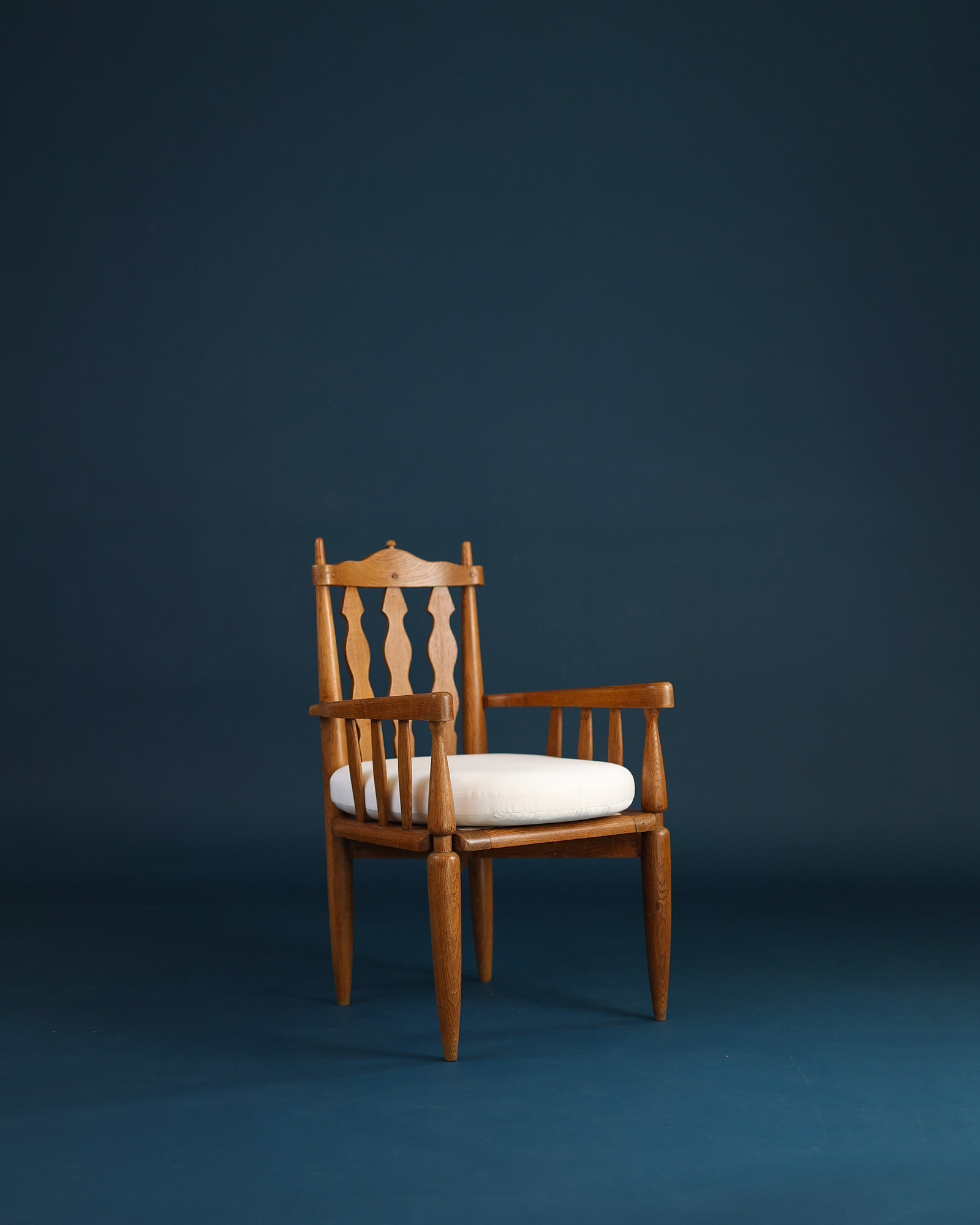 Unknown 1950s wooden armchair - three-quarter front view with striped upholstery on a dark blue background
