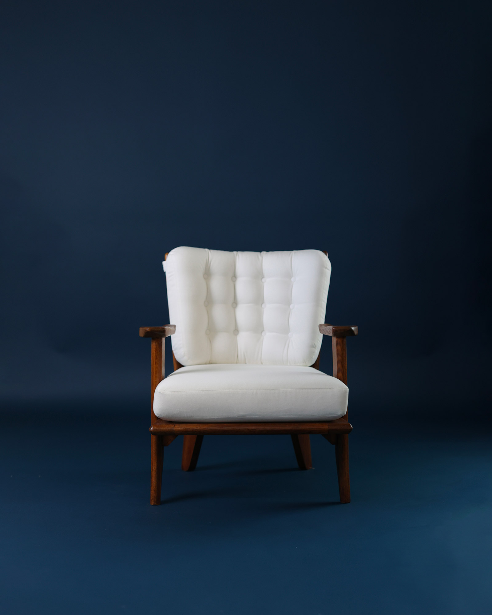 Catherine armchair by Guillerme et Chambron - full front view featuring white button-tufted upholstery and solid oak frame on a dark blue background