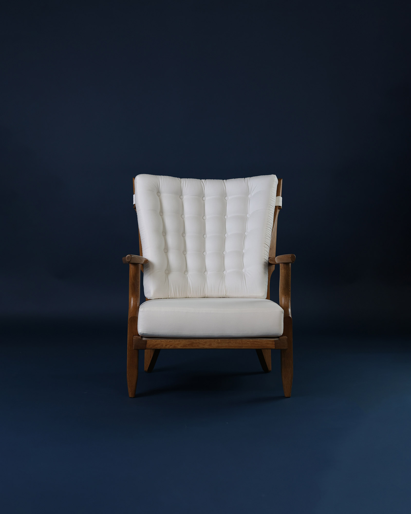 Petit Repos armchair by Guillerme et Chambron - full front view featuring white fabric upholstery and solid oak frame on a dark background