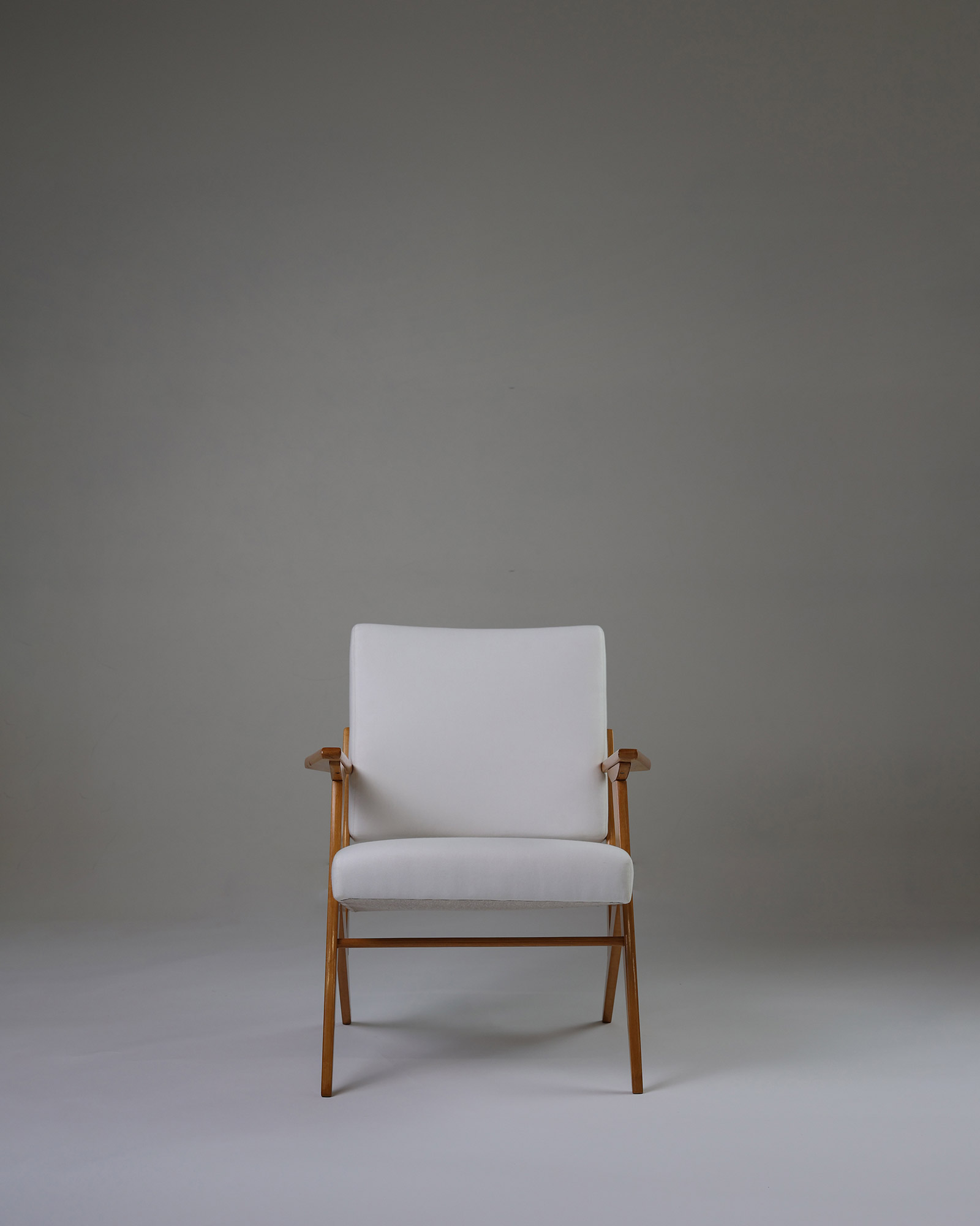 Pair of armchairs by José Zanine Caldas - full front view of a single chair with solid wood frame and light upholstery