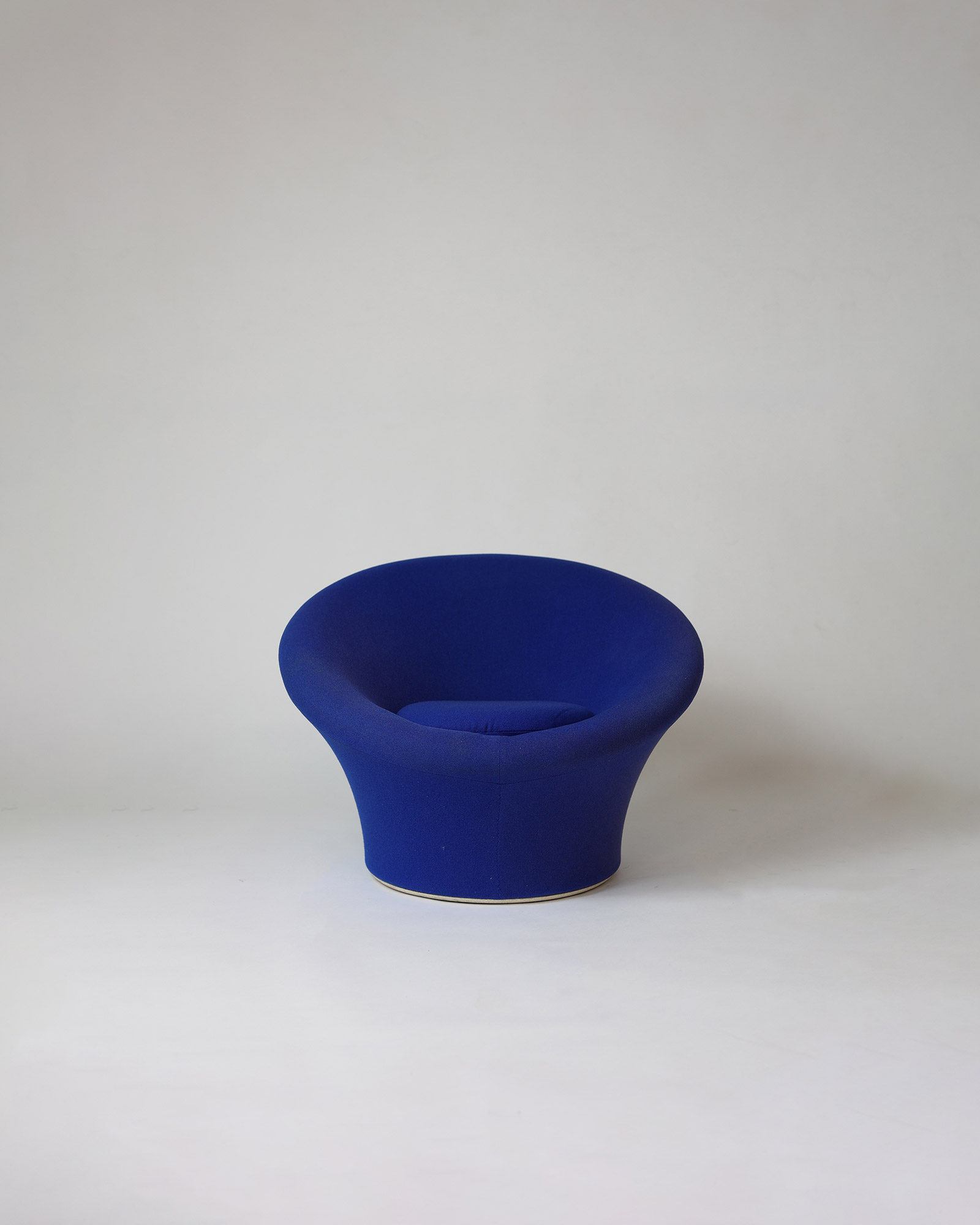 A three-quarter front view from above, showing the distinct round form of a dark blue upholstered Pierre Paulin Mushroom lounge chair.