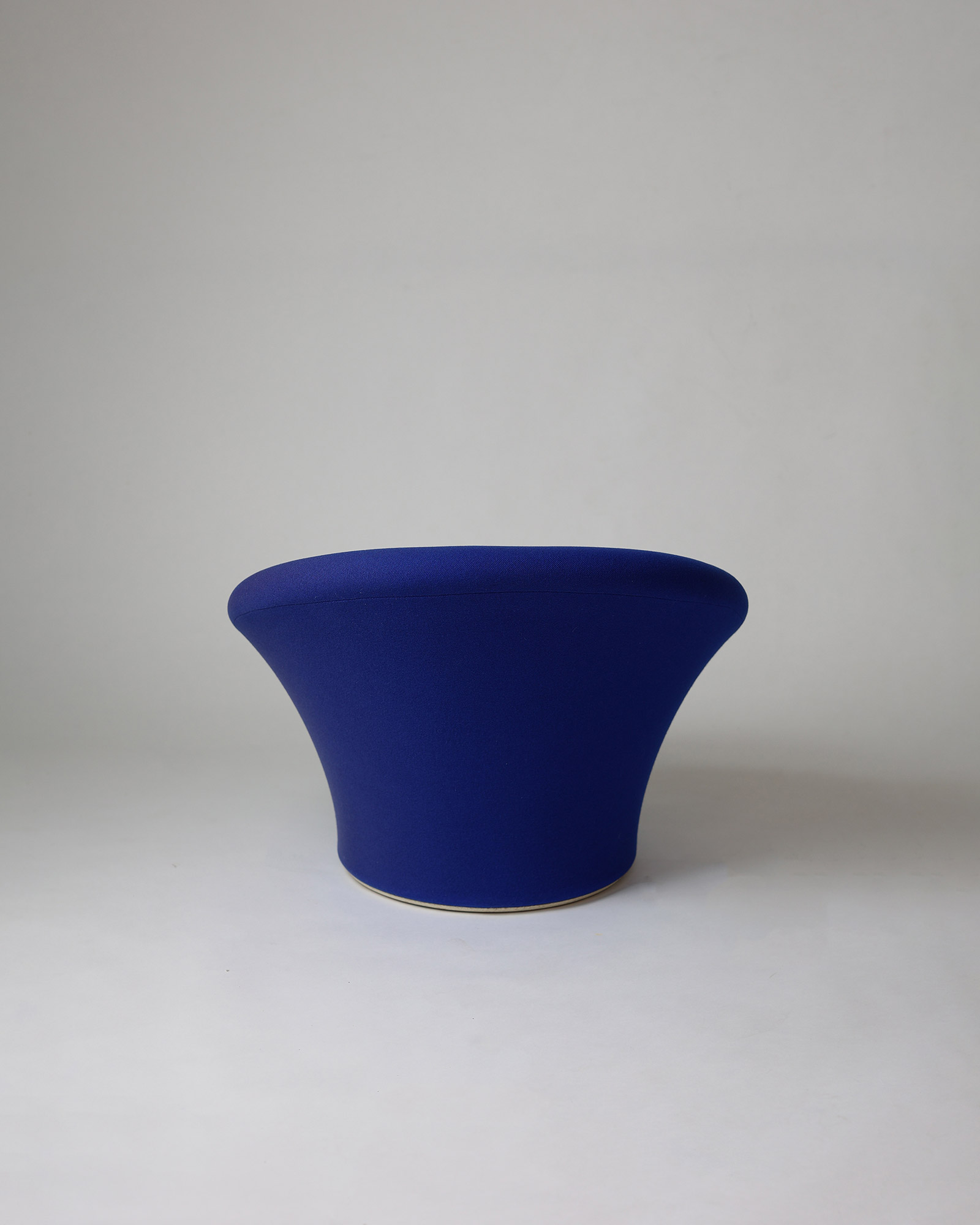A low three-quarter profile view of a dark blue upholstered Pierre Paulin Mushroom lounge chair, showing its continuous structure.